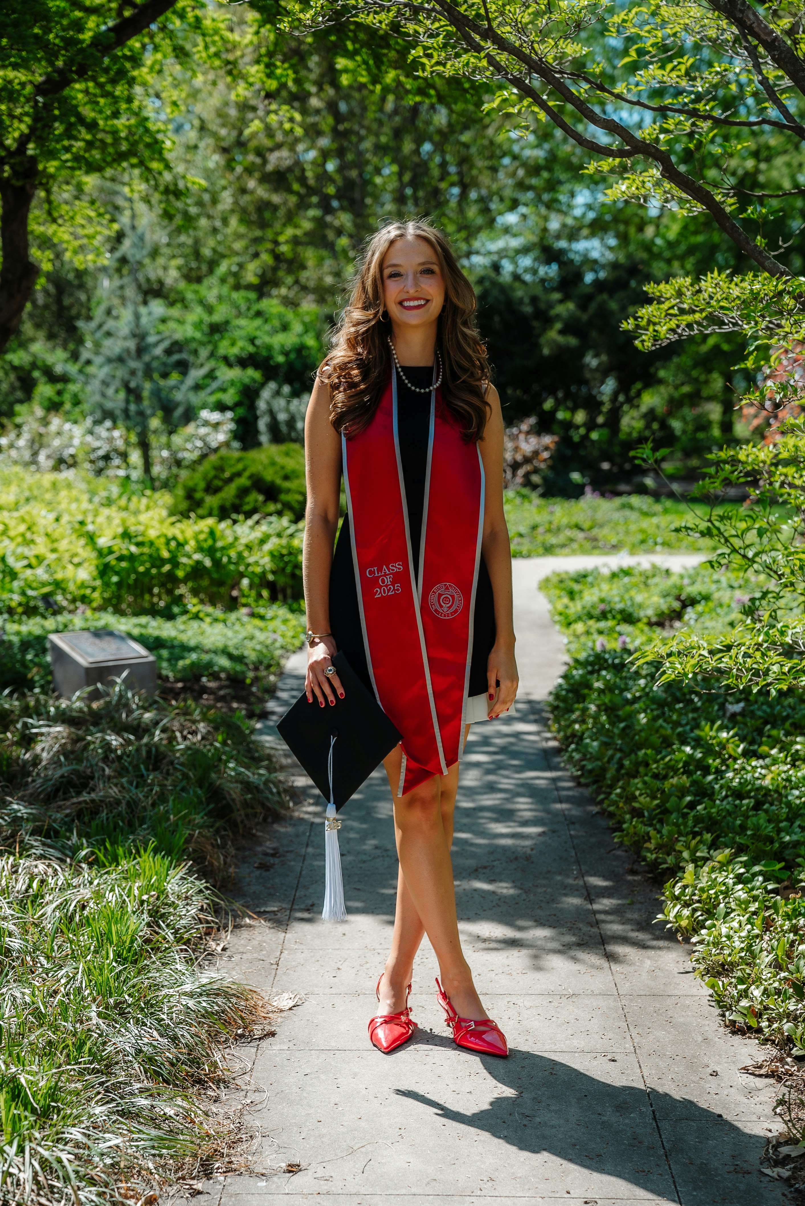 Eine lächelnde Frau feiert ihren Abschluss im Freien.