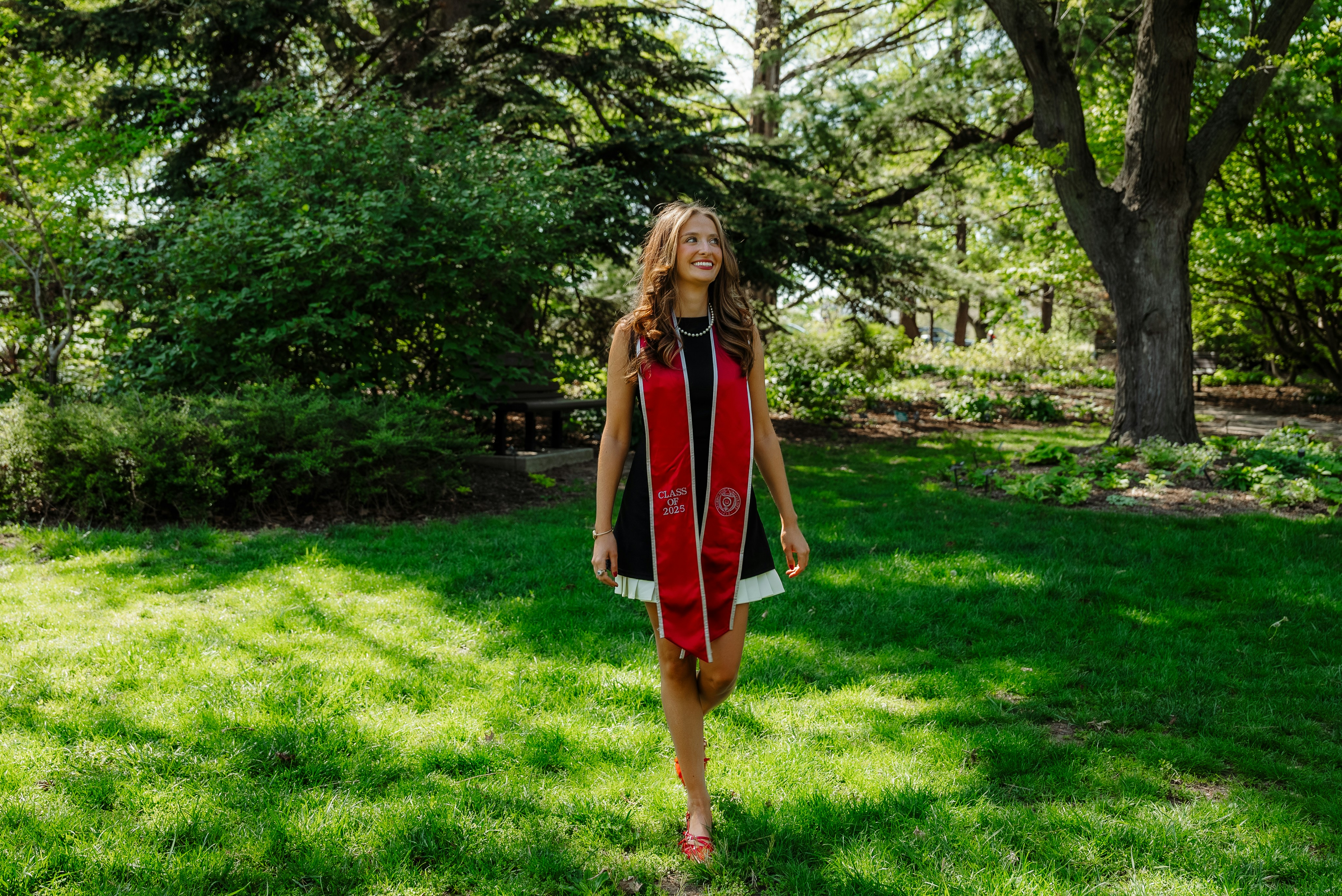 Ein Absolvent lächelt, während er im Park spazieren geht.