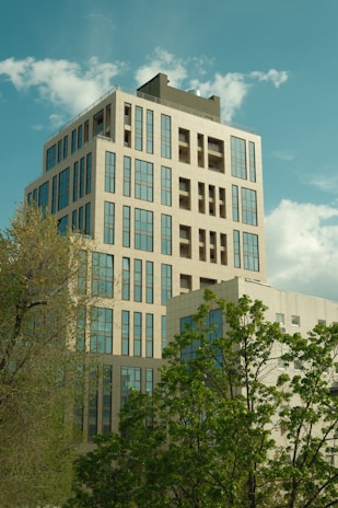 Modern building rises towards a cloudy, blue sky.
