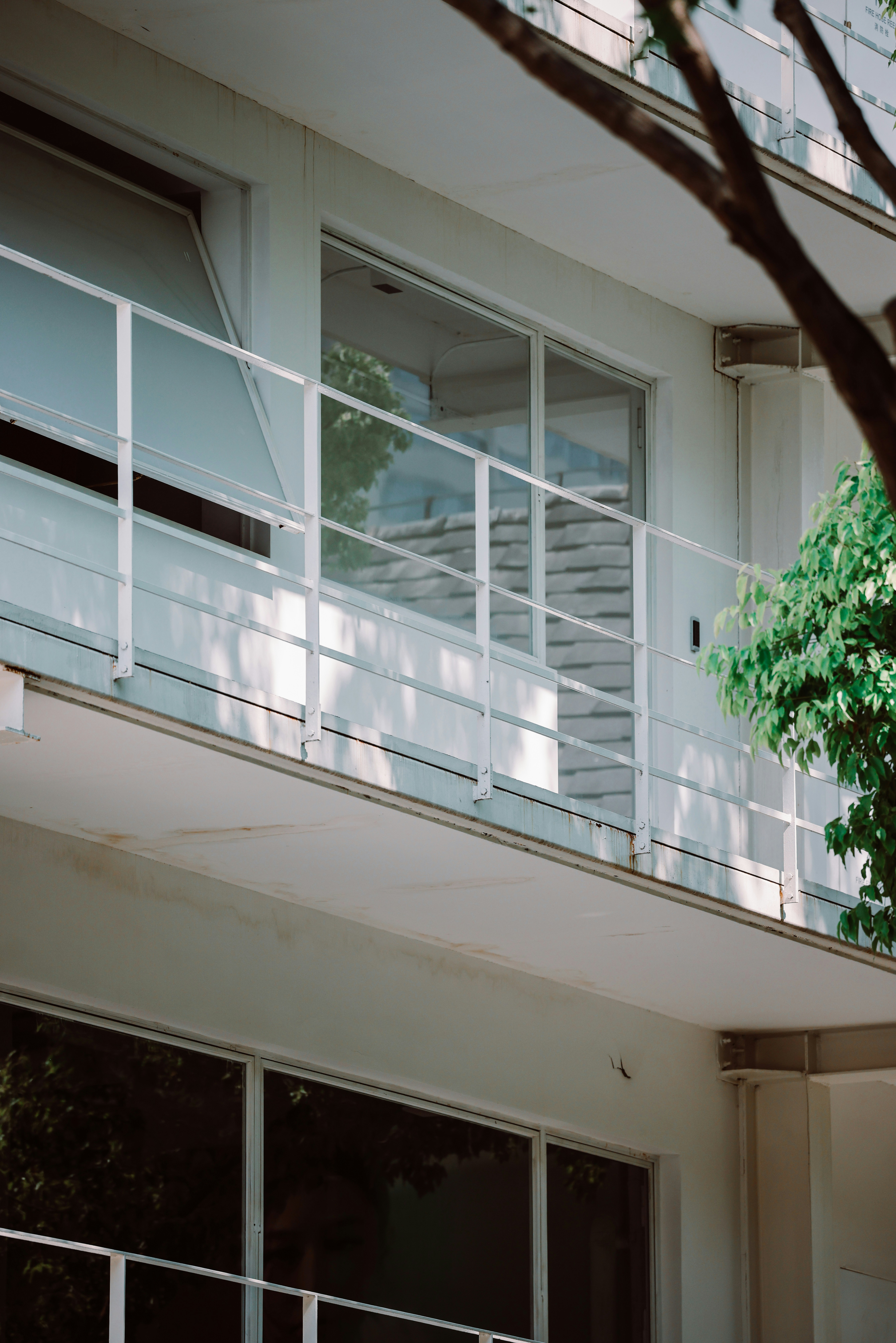 Modern white building with a balcony and glass windows.