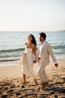 Newlyweds happily run along the beach.
