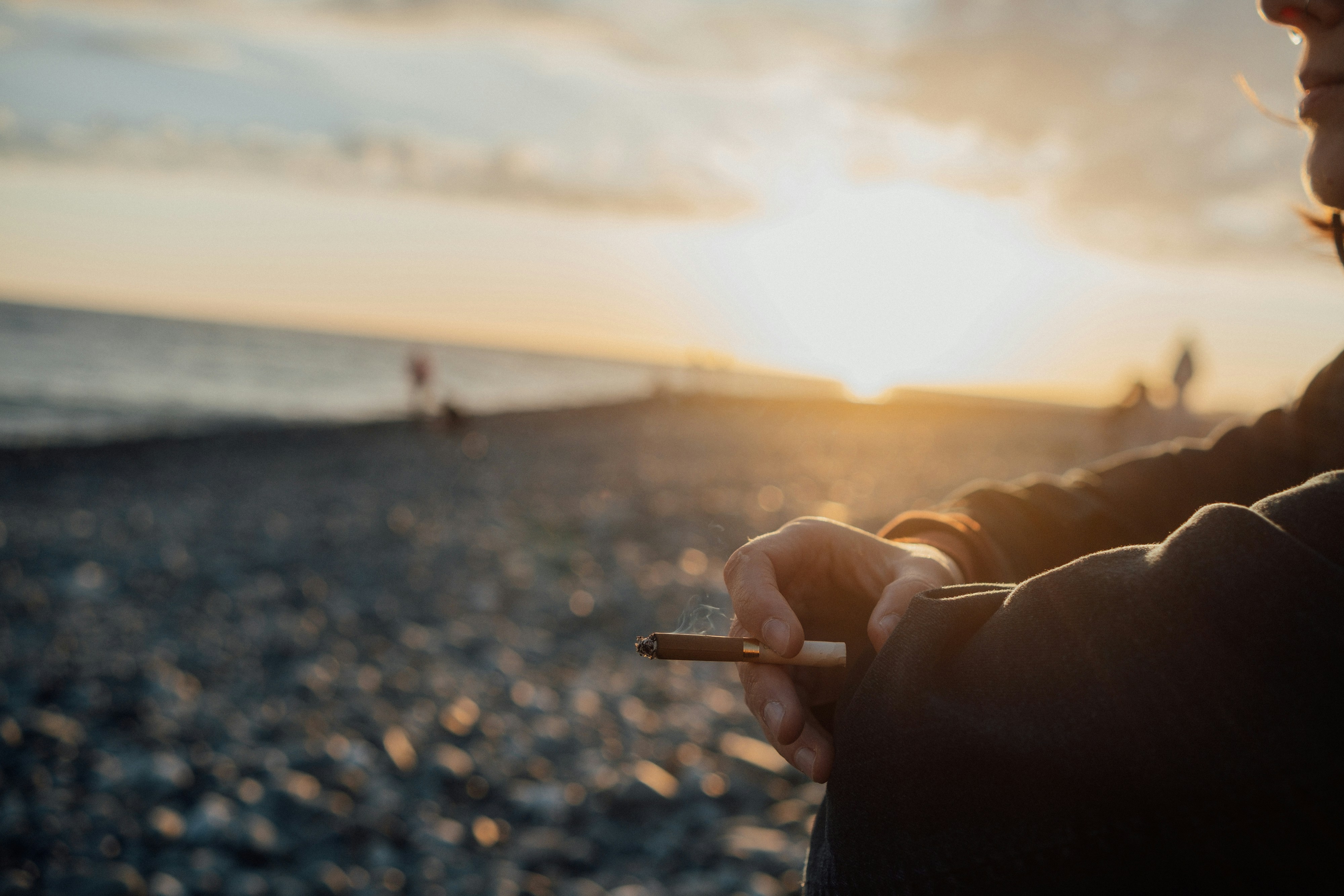 Person enjoys a moment by the beach with a sunset.