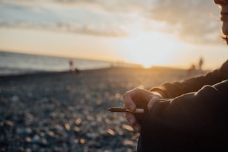 Person enjoys a moment by the beach with a sunset.