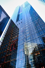 Glass skyscrapers reflect neighboring buildings and sky.