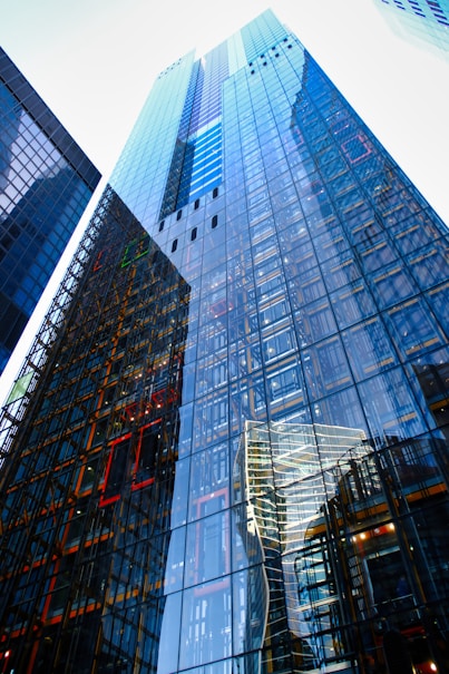 Glass skyscrapers reflect neighboring buildings and sky.