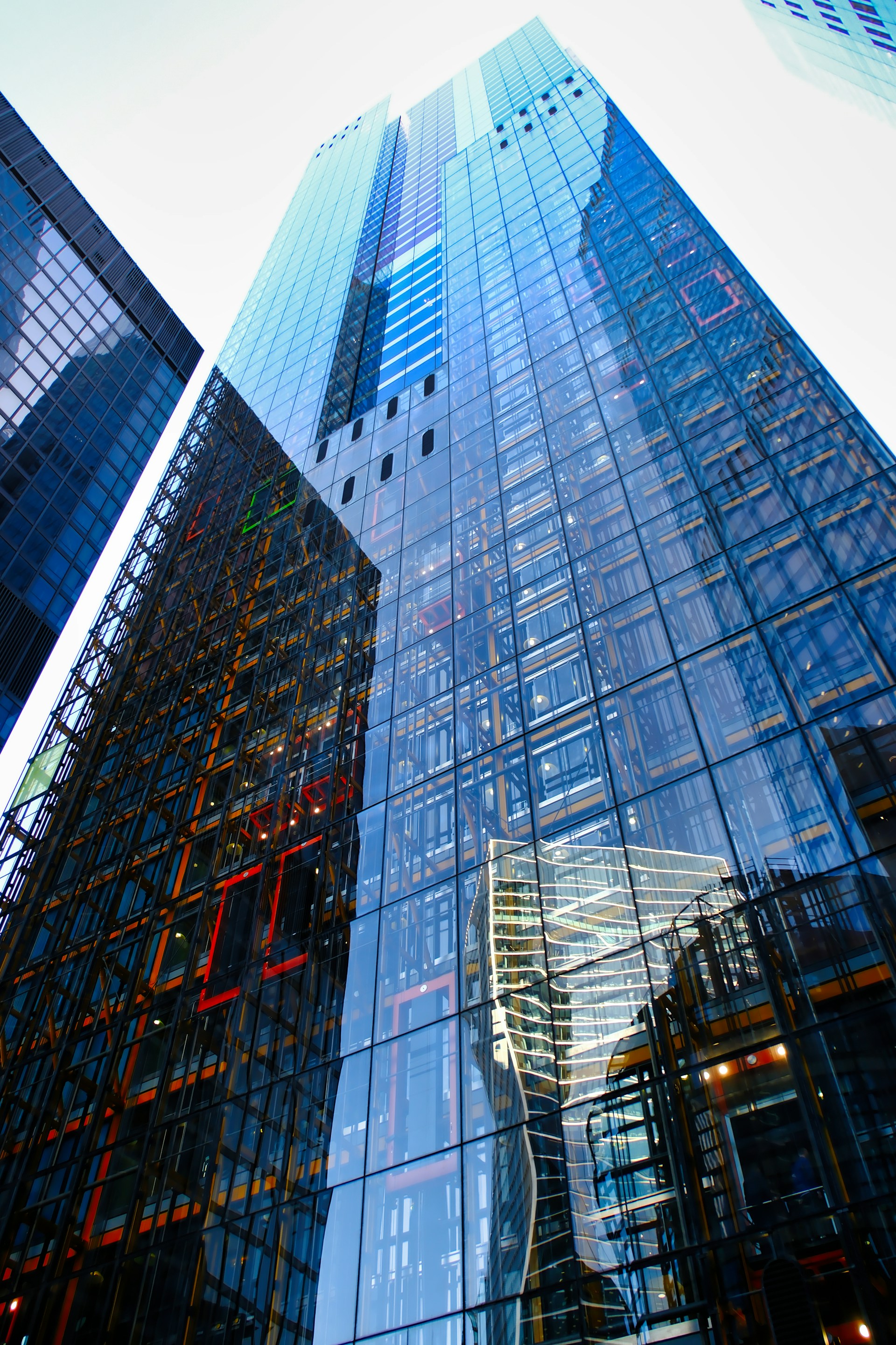 Glass skyscrapers reflect neighboring buildings and sky.