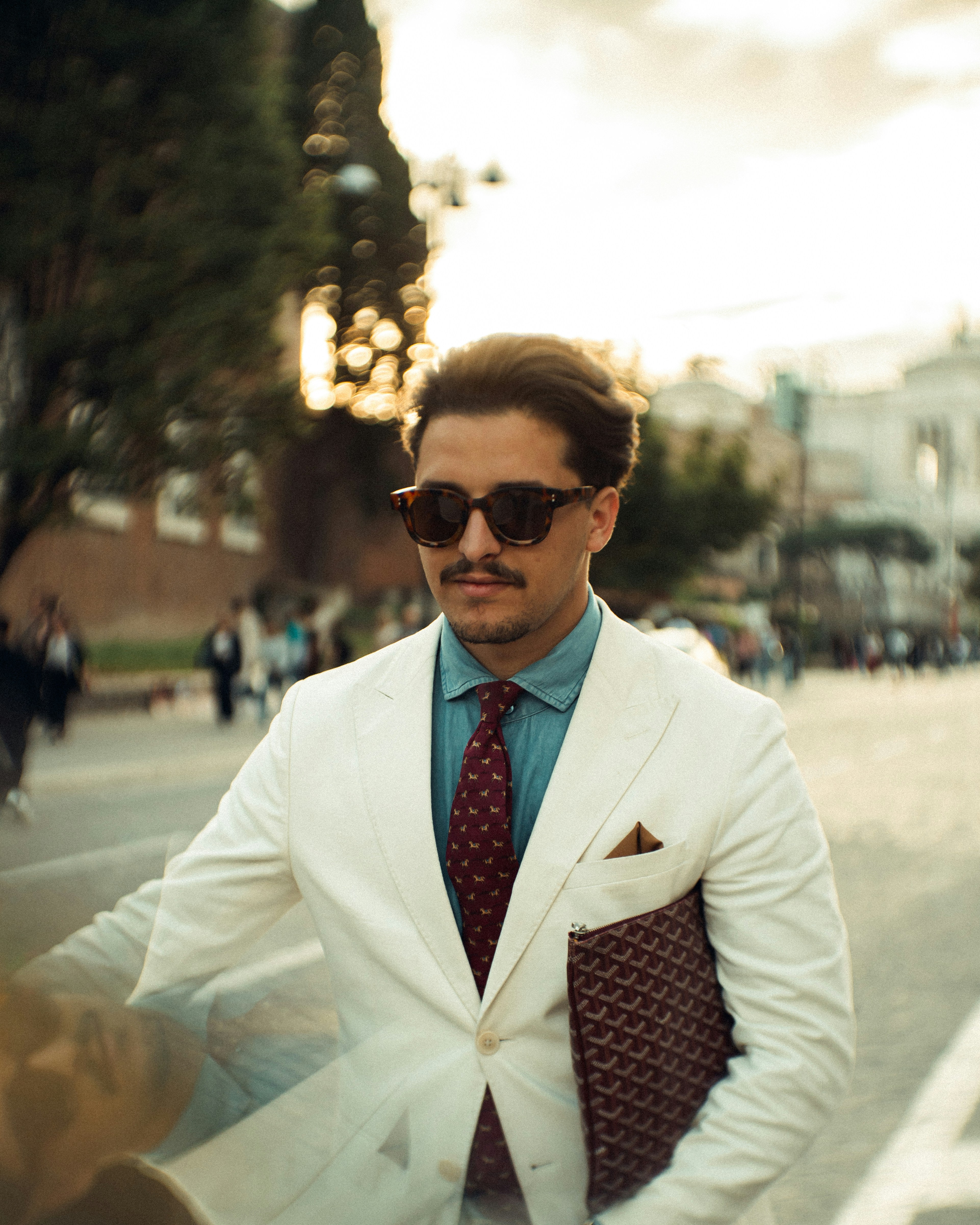Stylish man in suit posing outdoors with a briefcase.