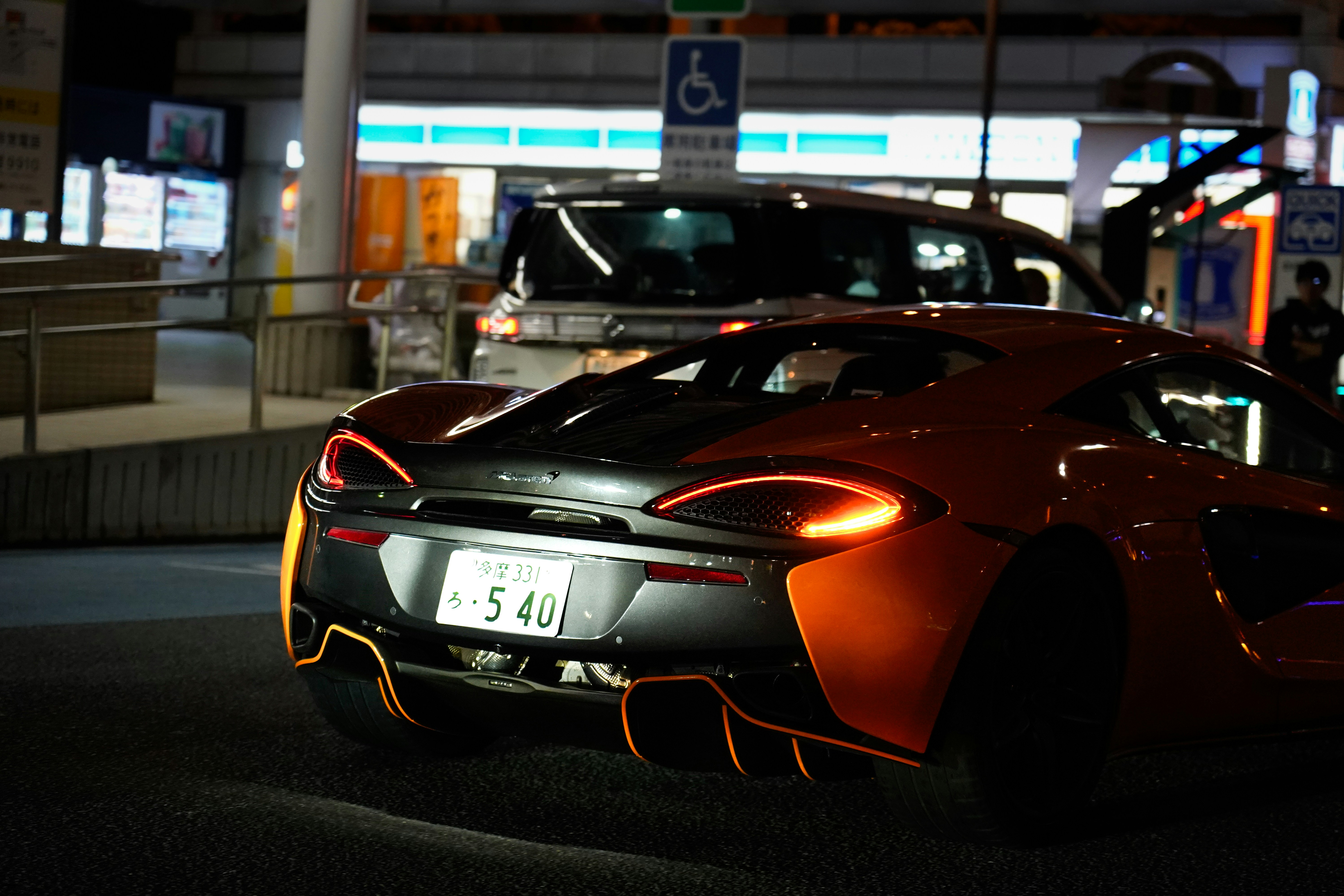 A sporty orange car parks at night.