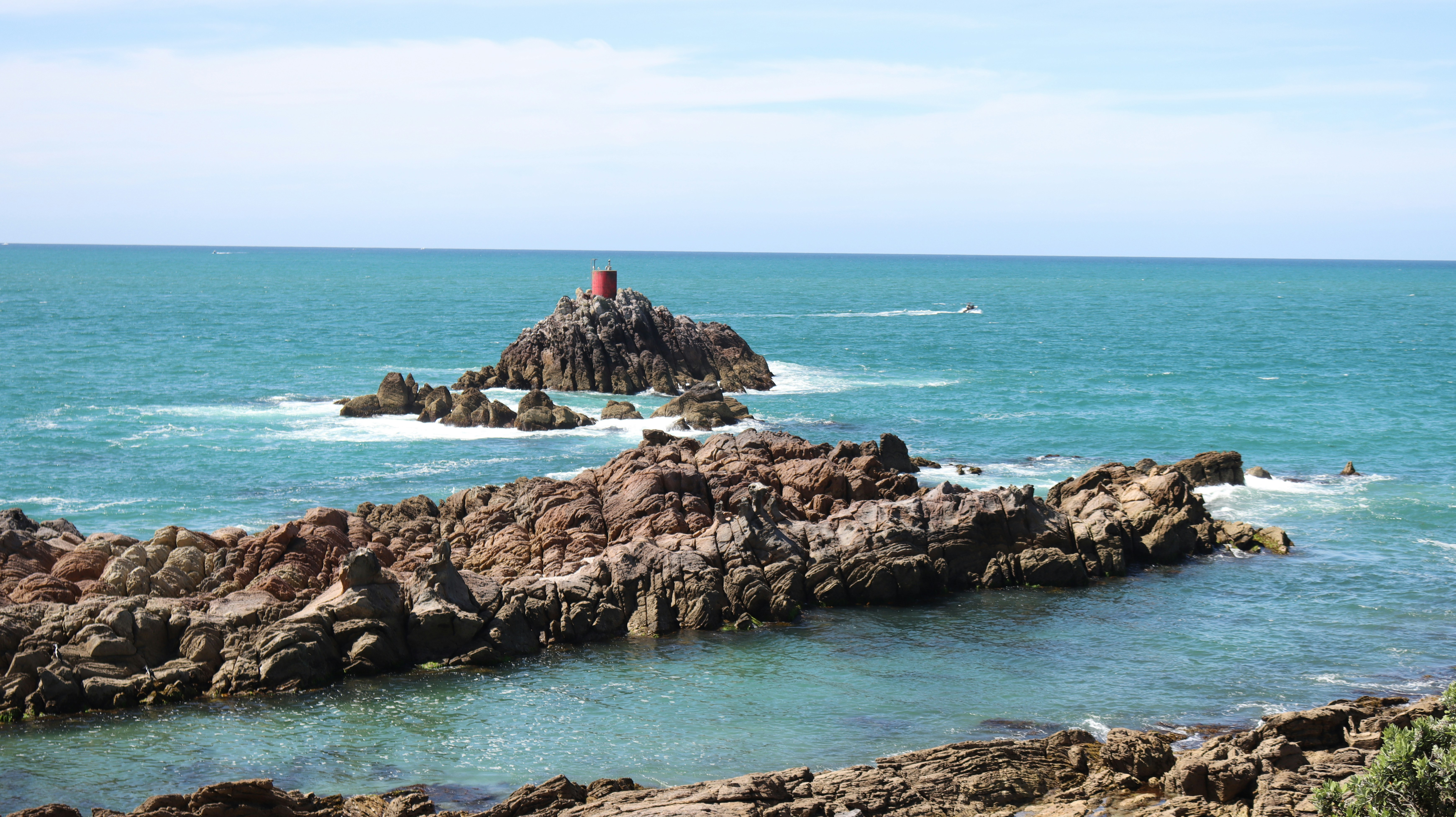 Rocky cliffs emerge from the sparkling blue ocean.