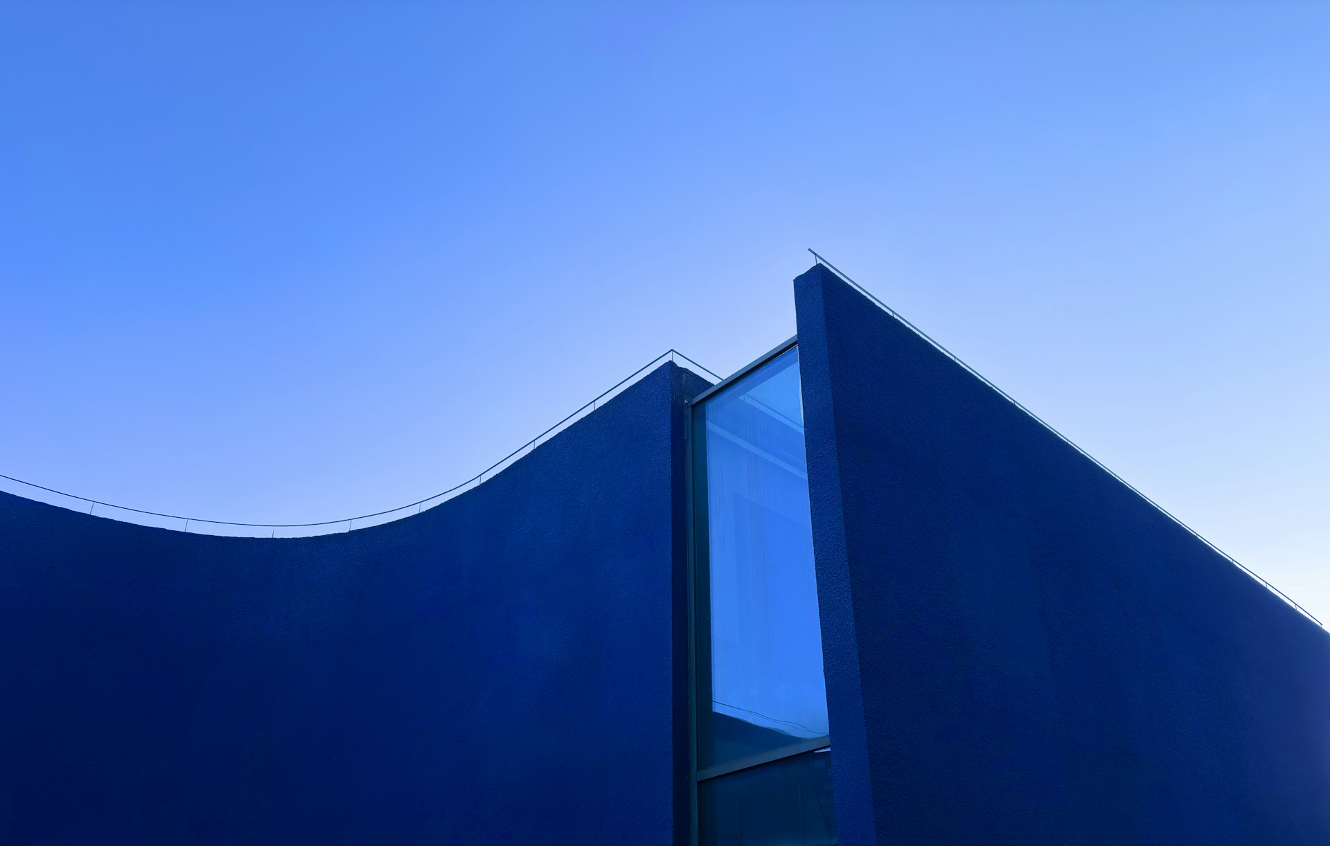 A modern, blue building against a clear sky.