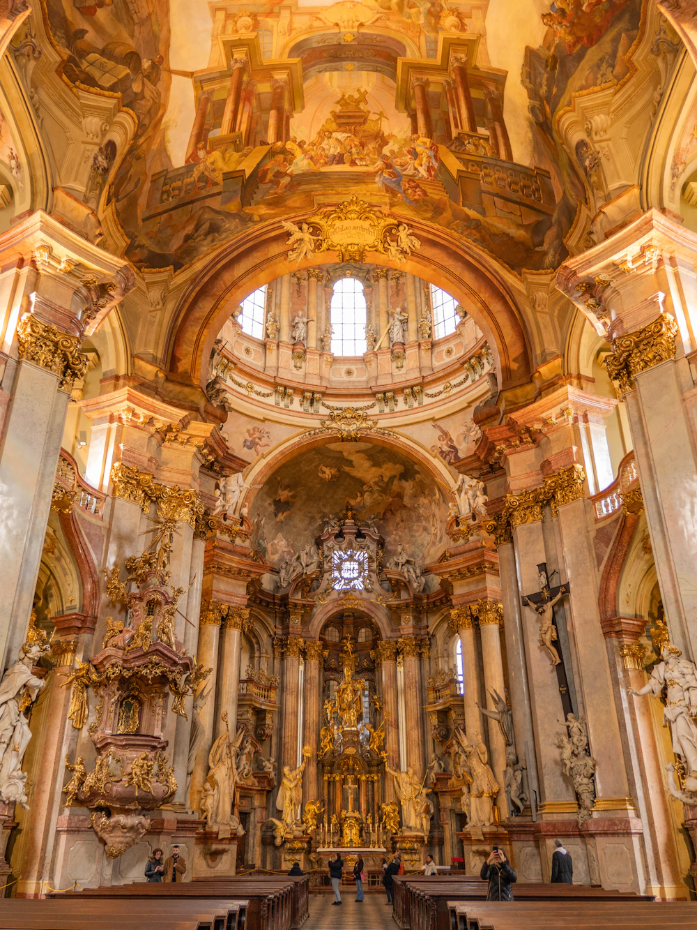 Interior de uma igreja barroca, com altar dourado, arcos e bancos de madeira