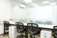 Office space with desks, chairs, and glass panels.