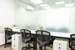 Office space with desks, chairs, and glass panels.