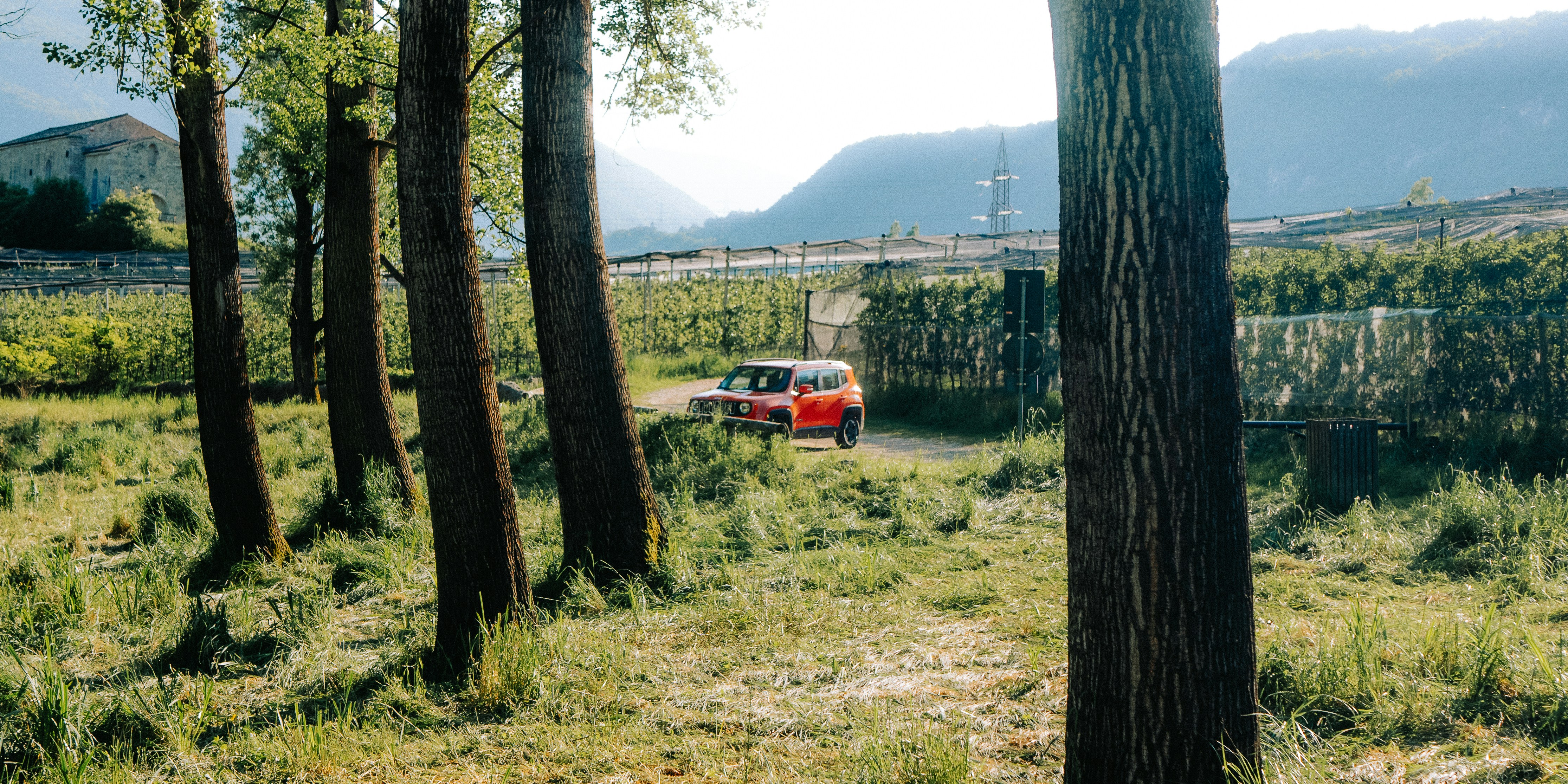 A red vehicle drives down a grassy path.