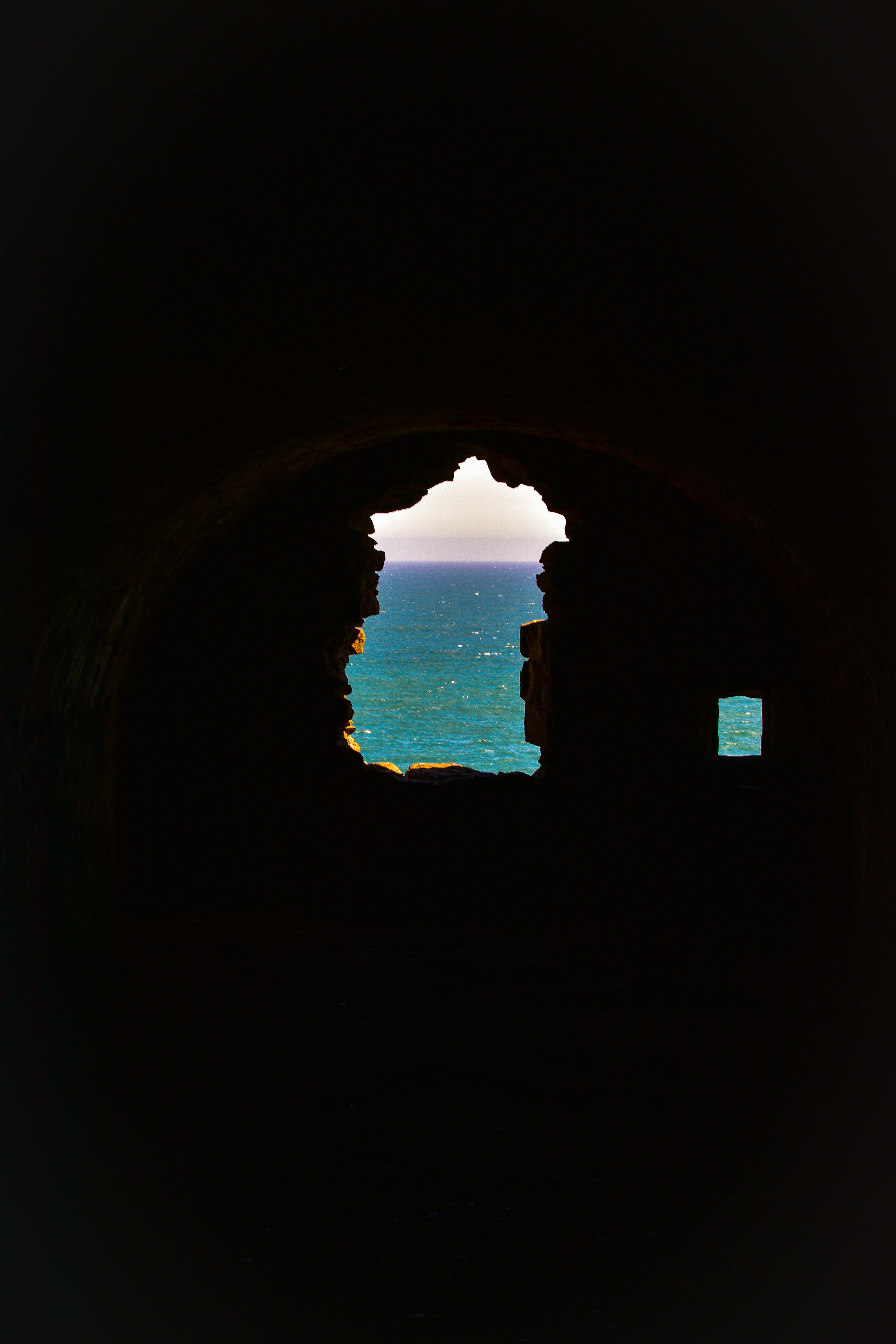 An ocean view glimpsed through a dark opening.