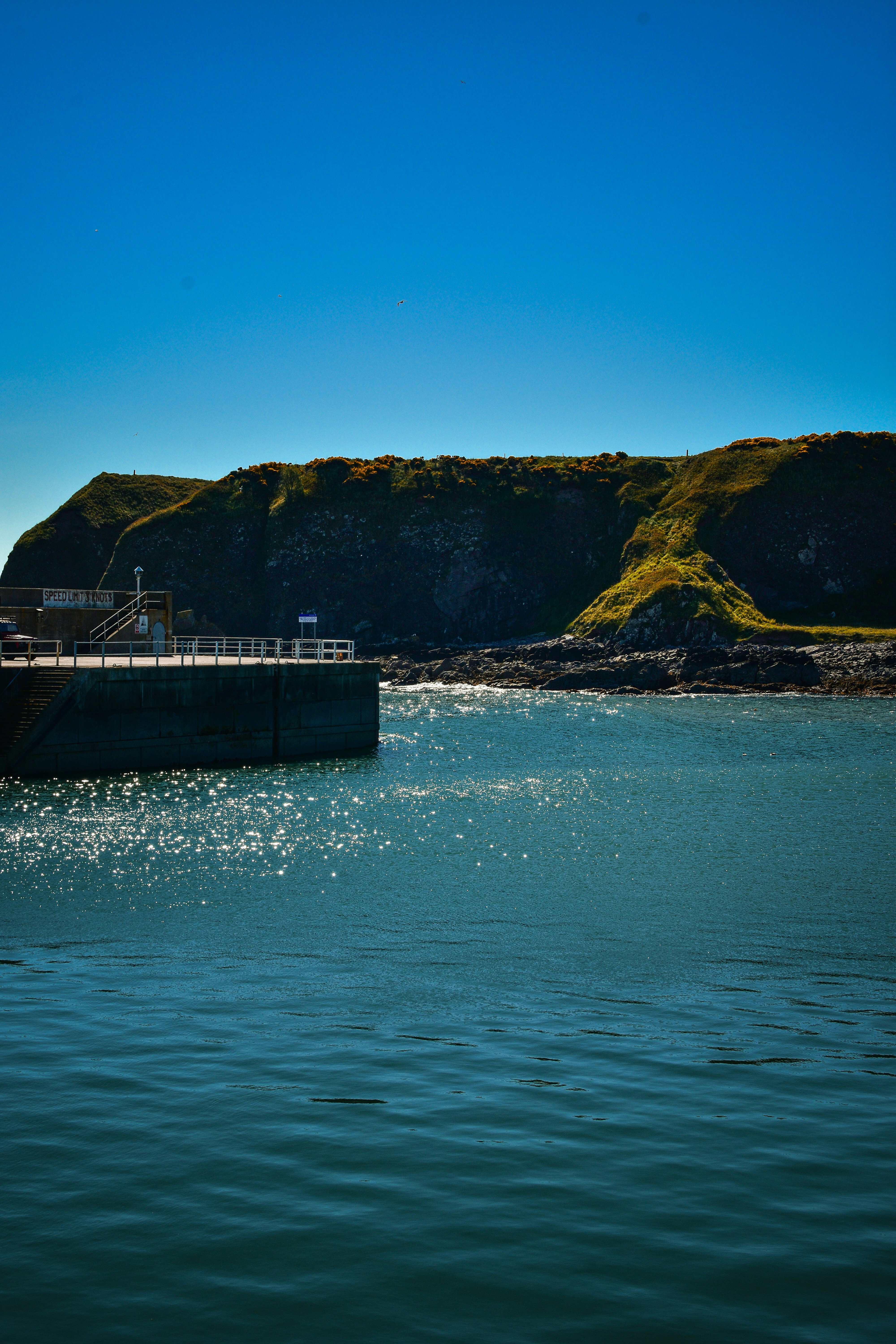 Ocean water near a rocky cliff and pier.