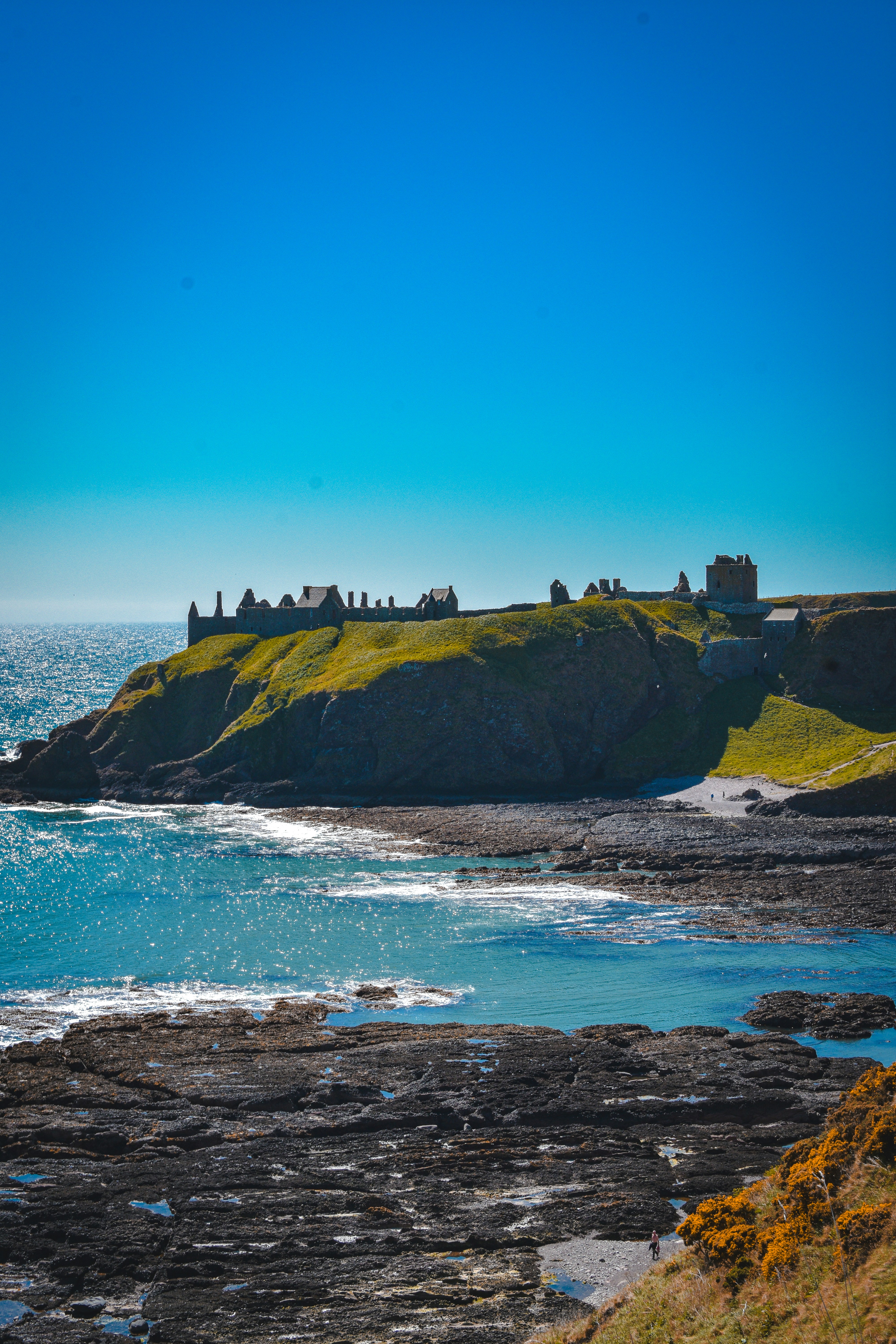 A castle sits high above the ocean.