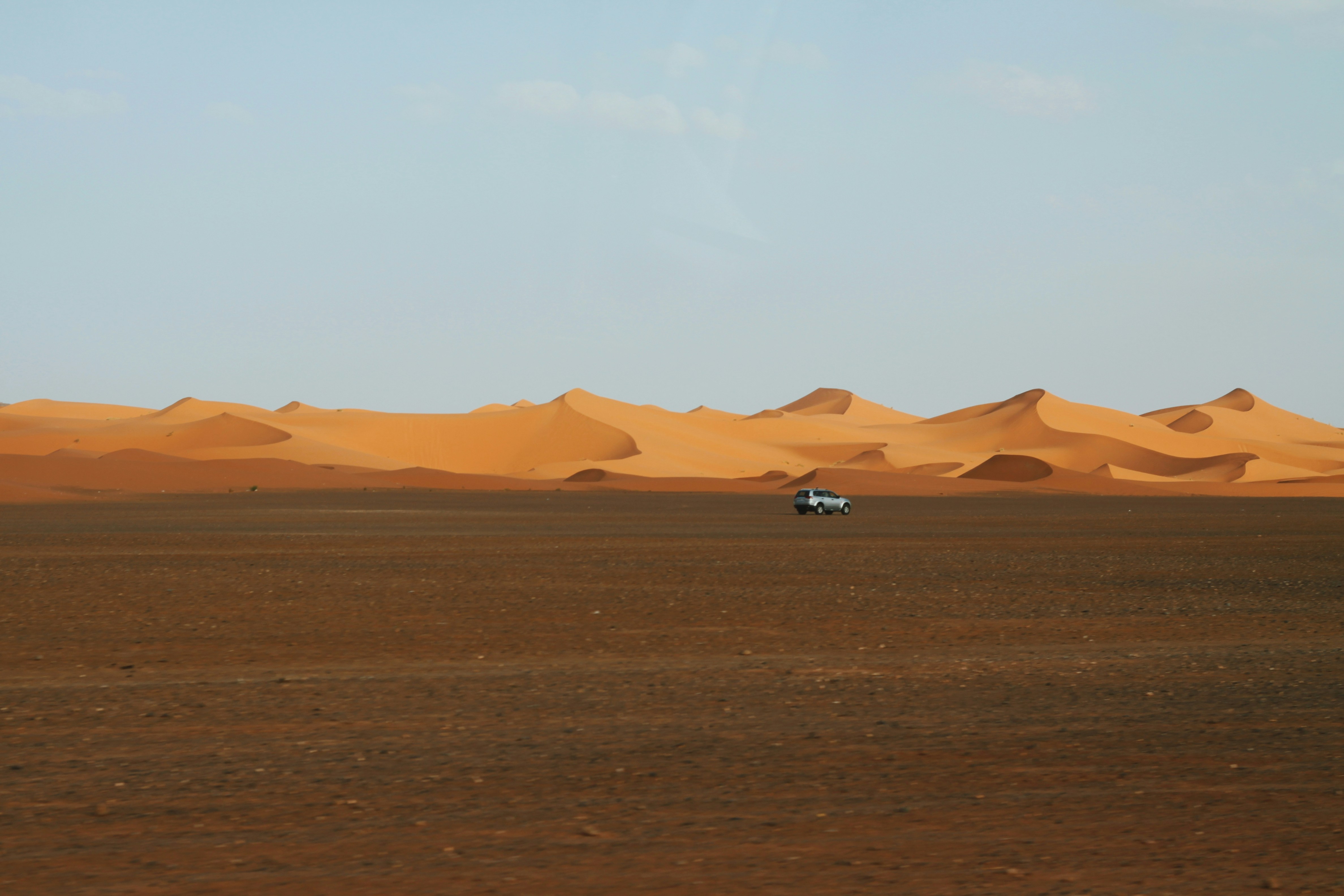 A car drives across a desert landscape.