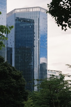 Glass skyscraper towers above the lush green trees.