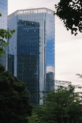 Glass skyscraper towers above the lush green trees.