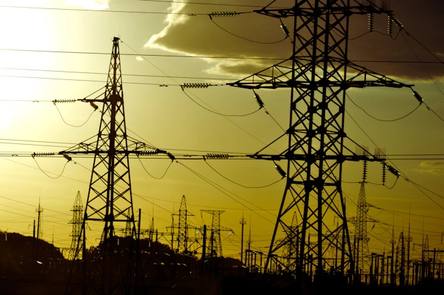 Power lines stand against a yellow sky.