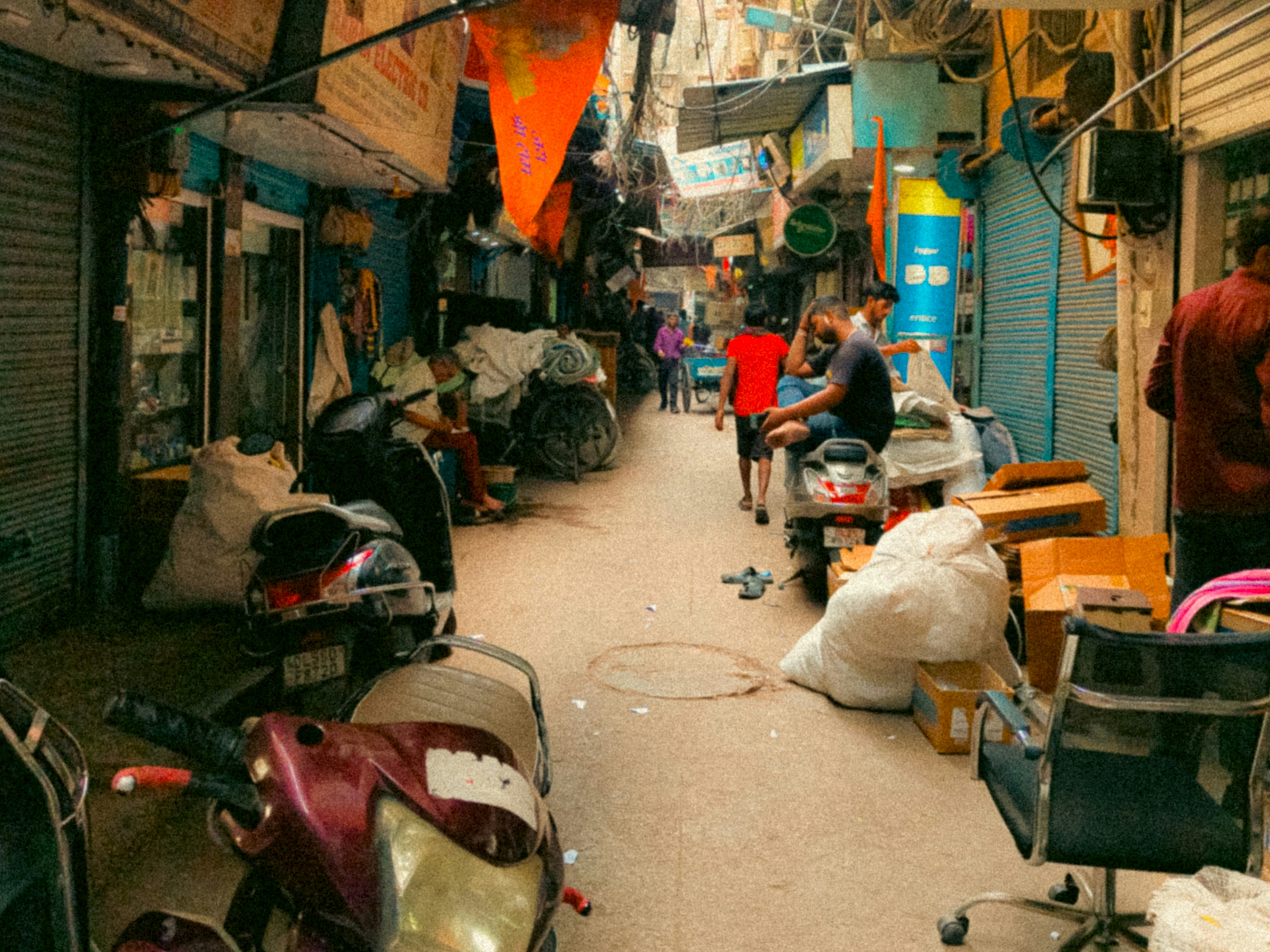 A crowded, narrow alleyway with people and scooters.