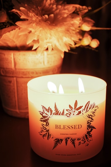 A lit candle with flowers and the word blessed.