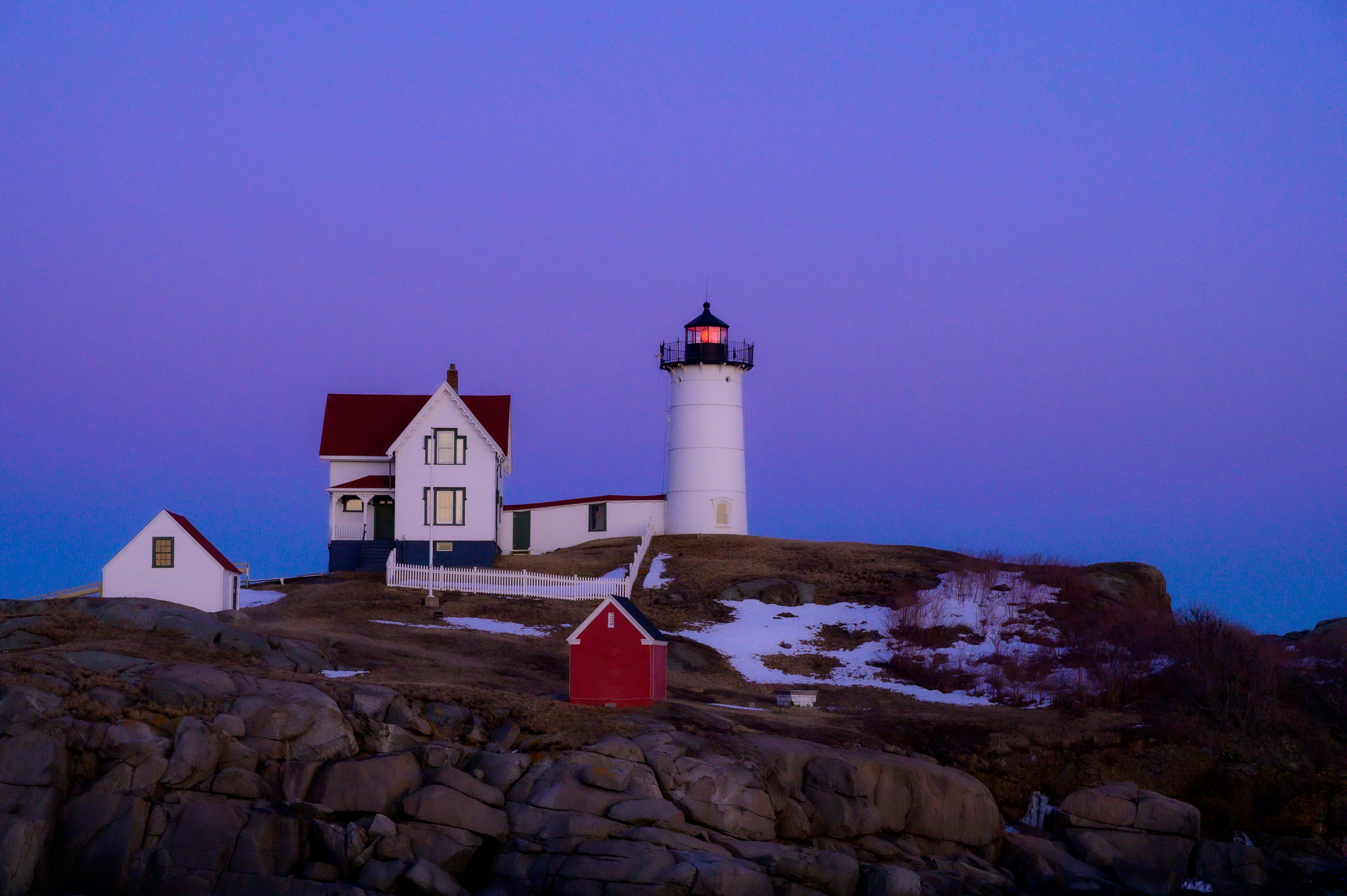 A lighthouse sits on a hill at twilight.