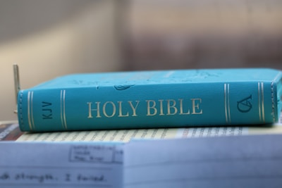 A teal holy bible is resting on a surface.