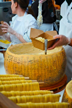 Fresh pasta is being served from a giant cheese wheel.