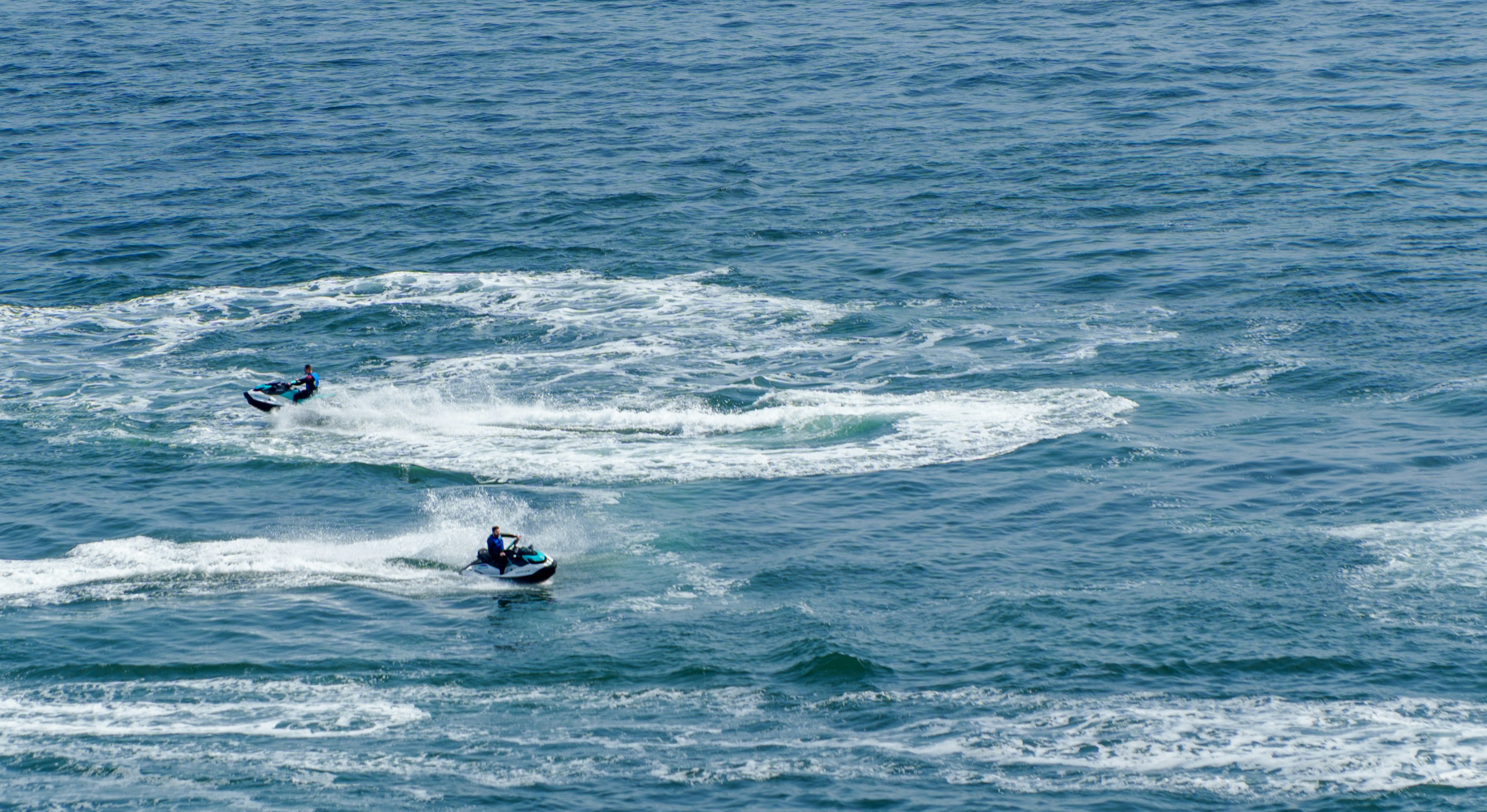 Jet skis race across the ocean's surface.