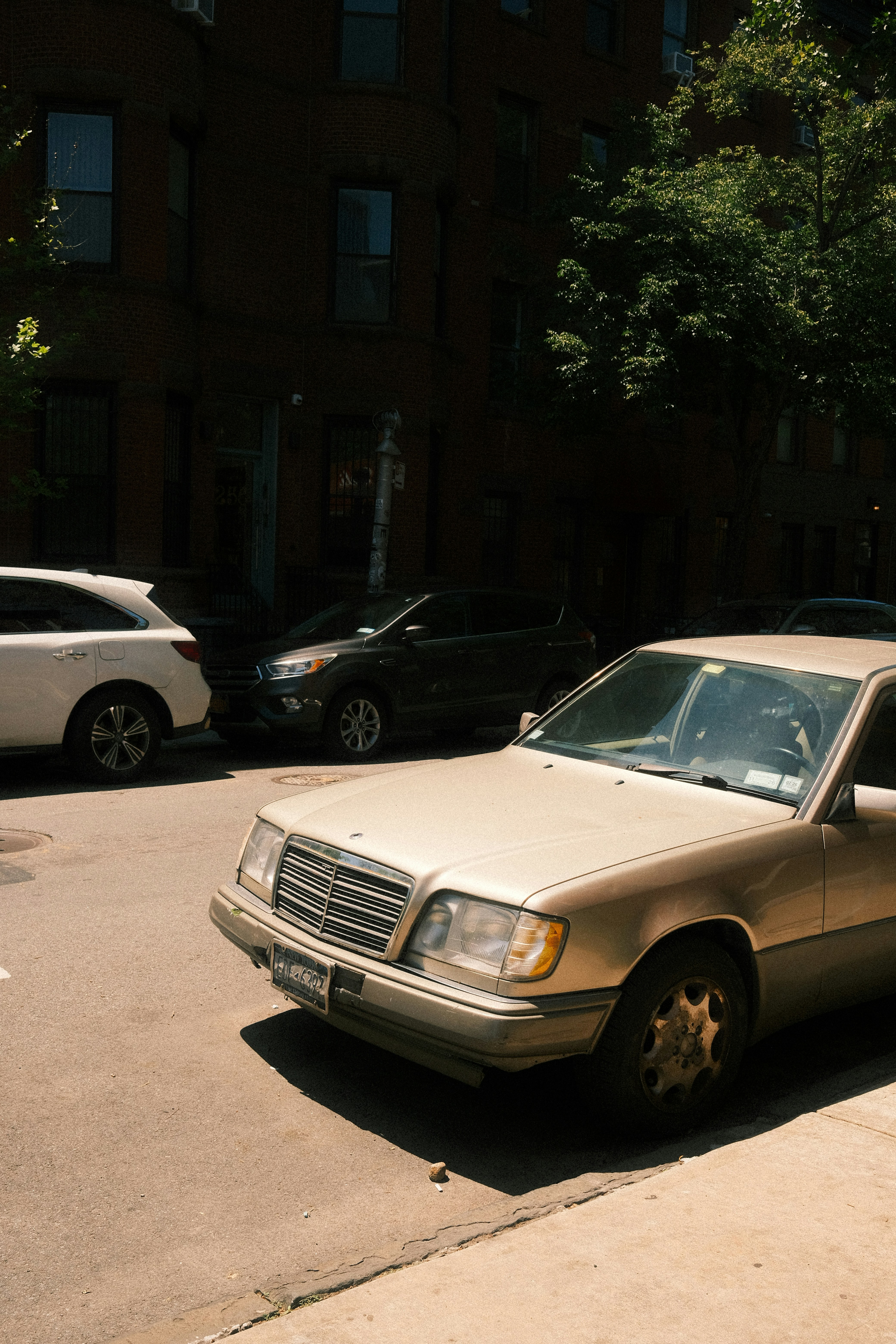 Cars are parked on a sunny city street.