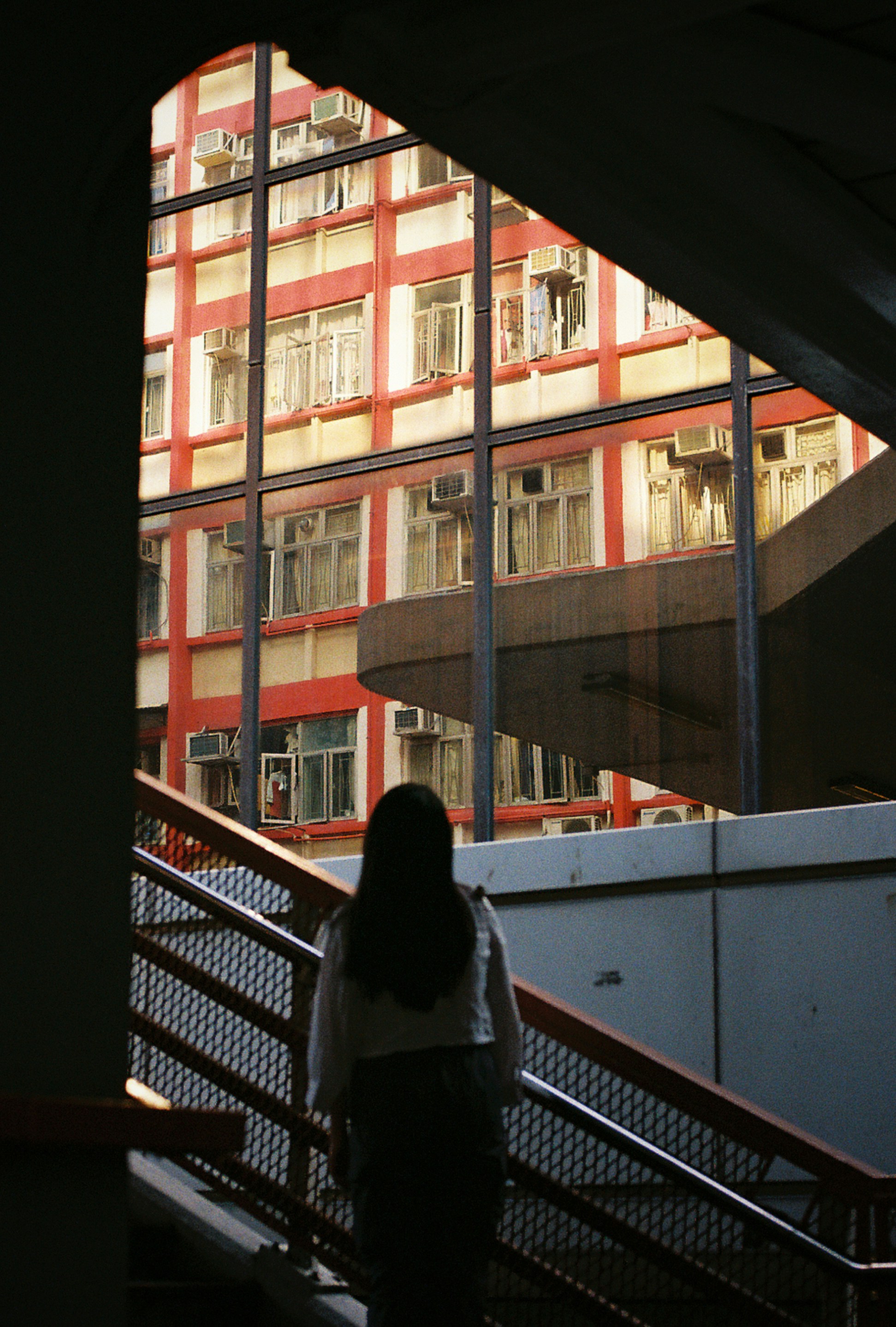 Woman ascends stairs in front of an orange building.