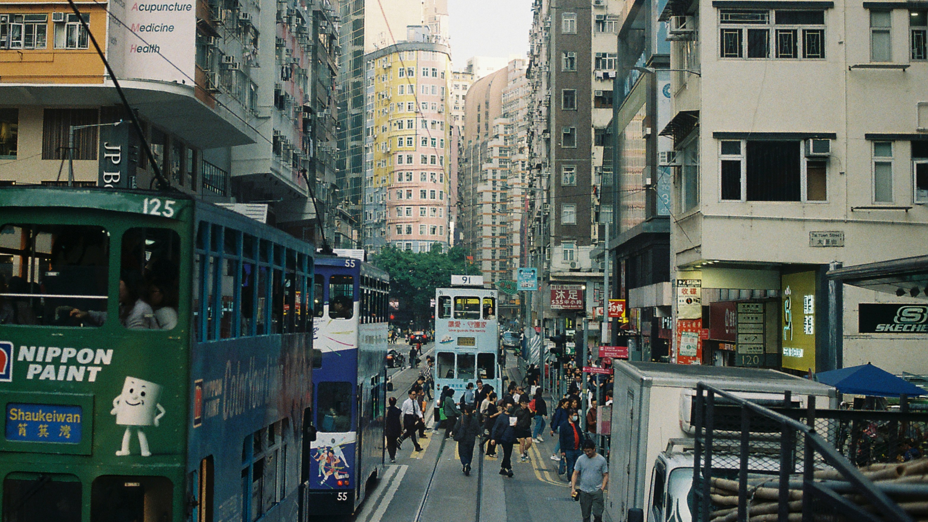 City street in hong kong with trams and people.