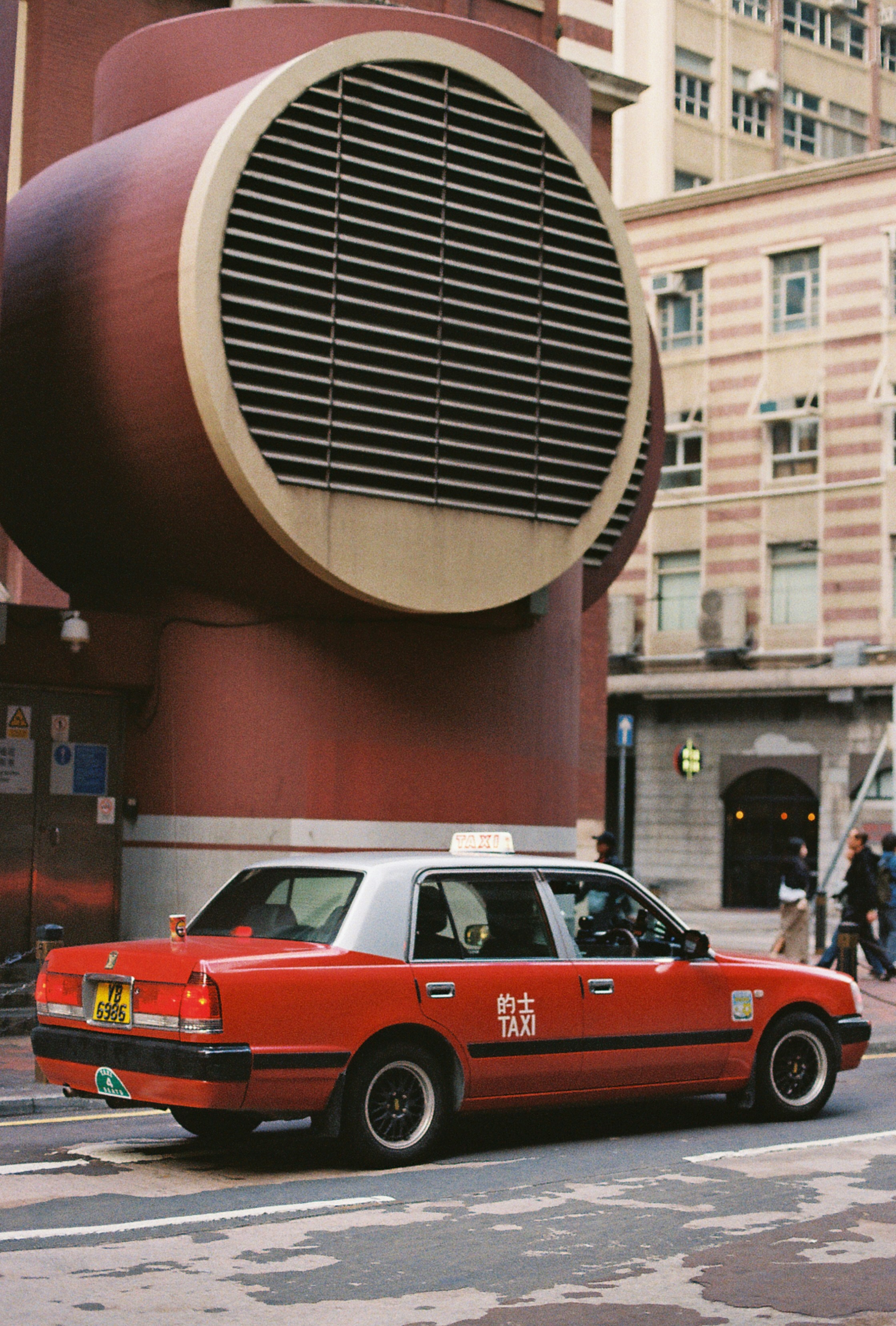A red taxi parks in front of a building.