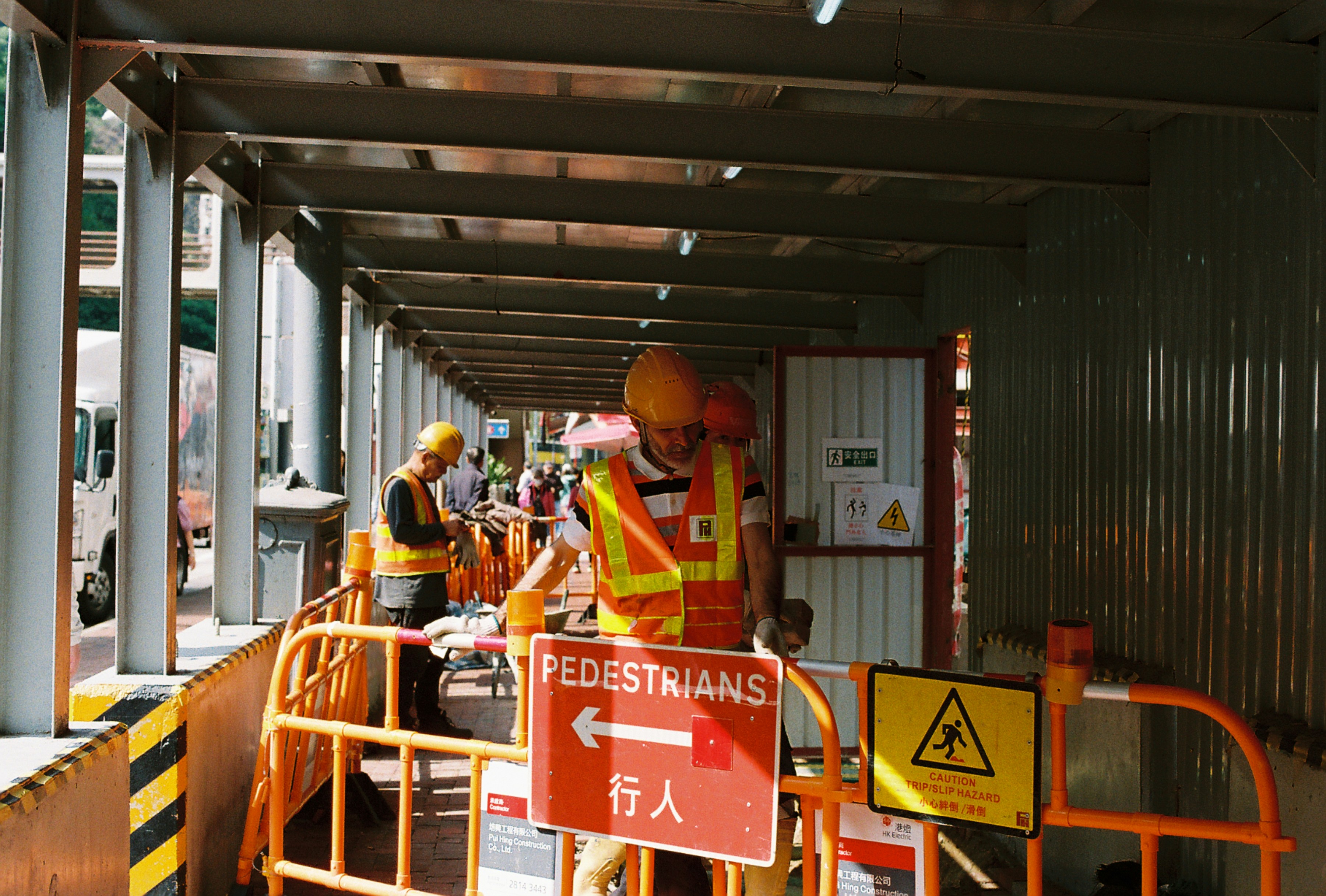 Construction workers are working near a pedestrian walkway.