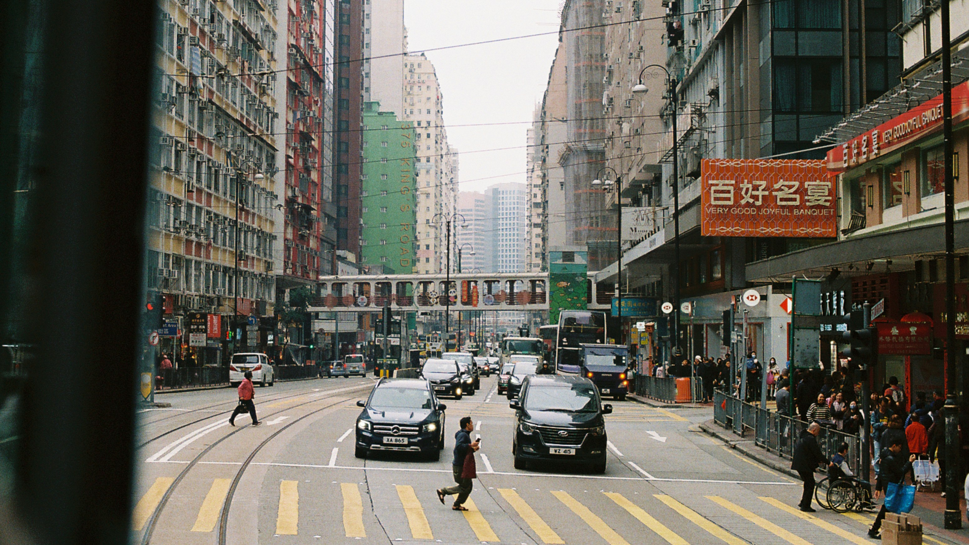 Busy hong kong street with cars and pedestrians.
