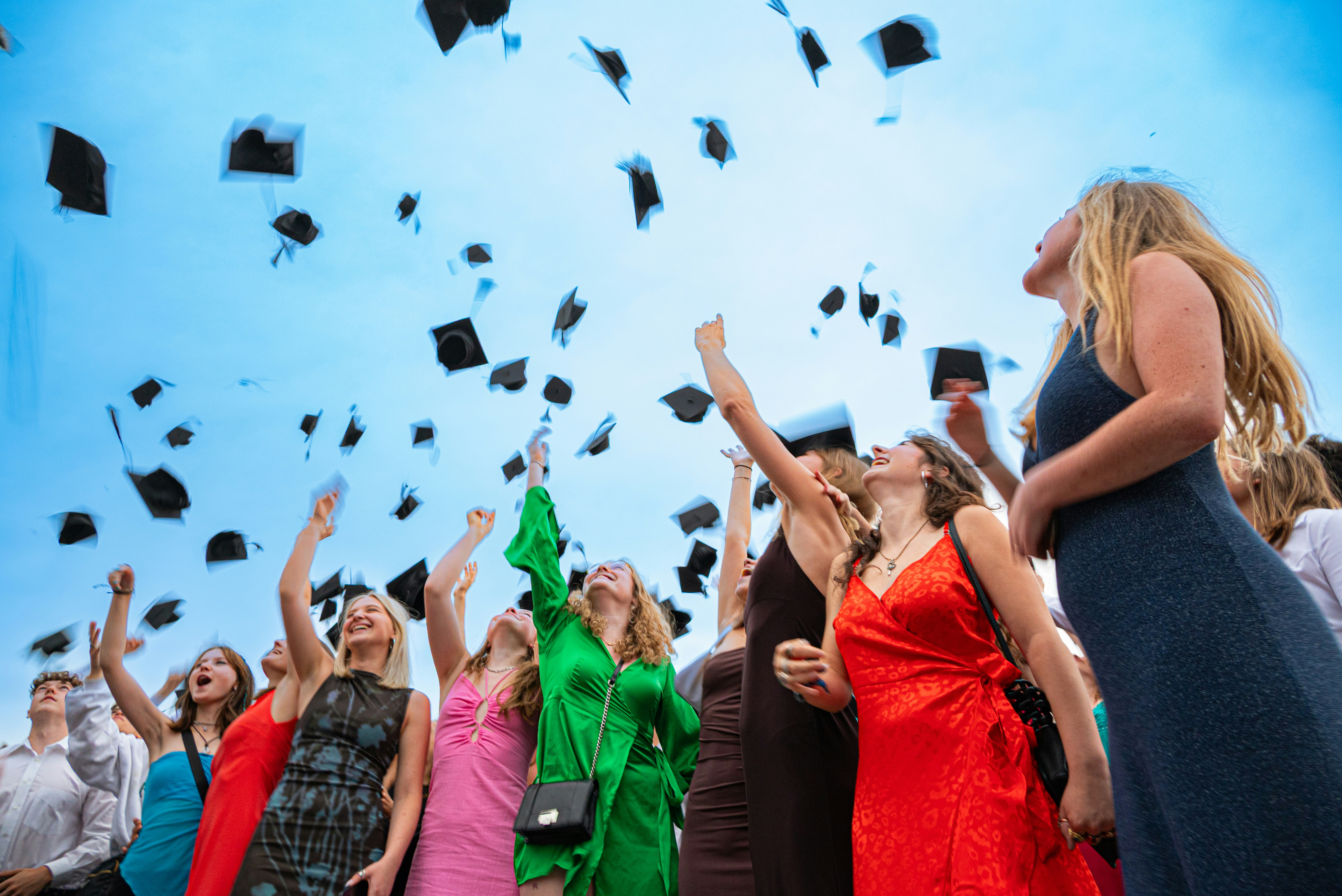 A diverse group of students in graduation caps throwing them in the air - Yearbook memories ideas