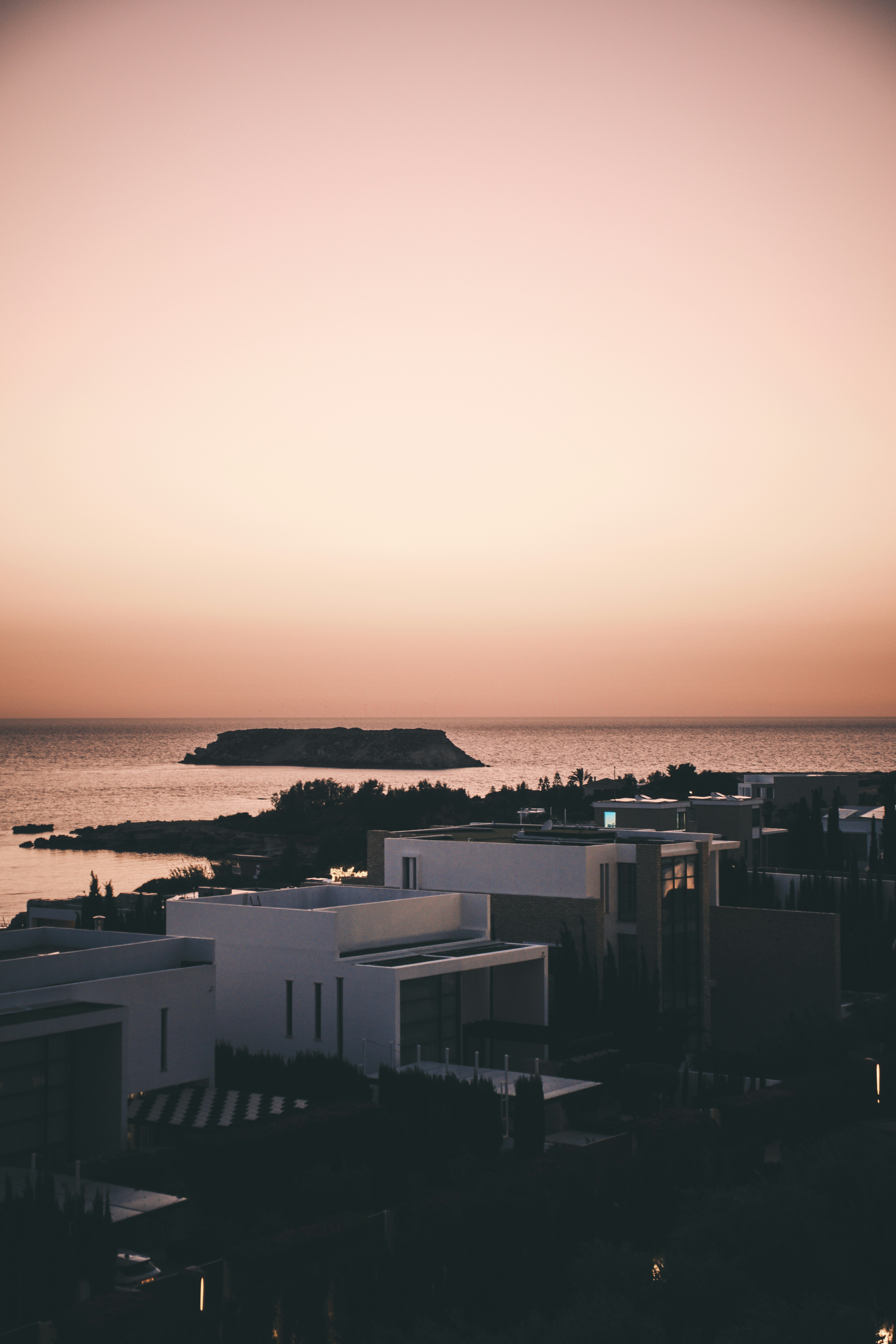 Pôr do sol sobre o oceano e edifícios modernos.