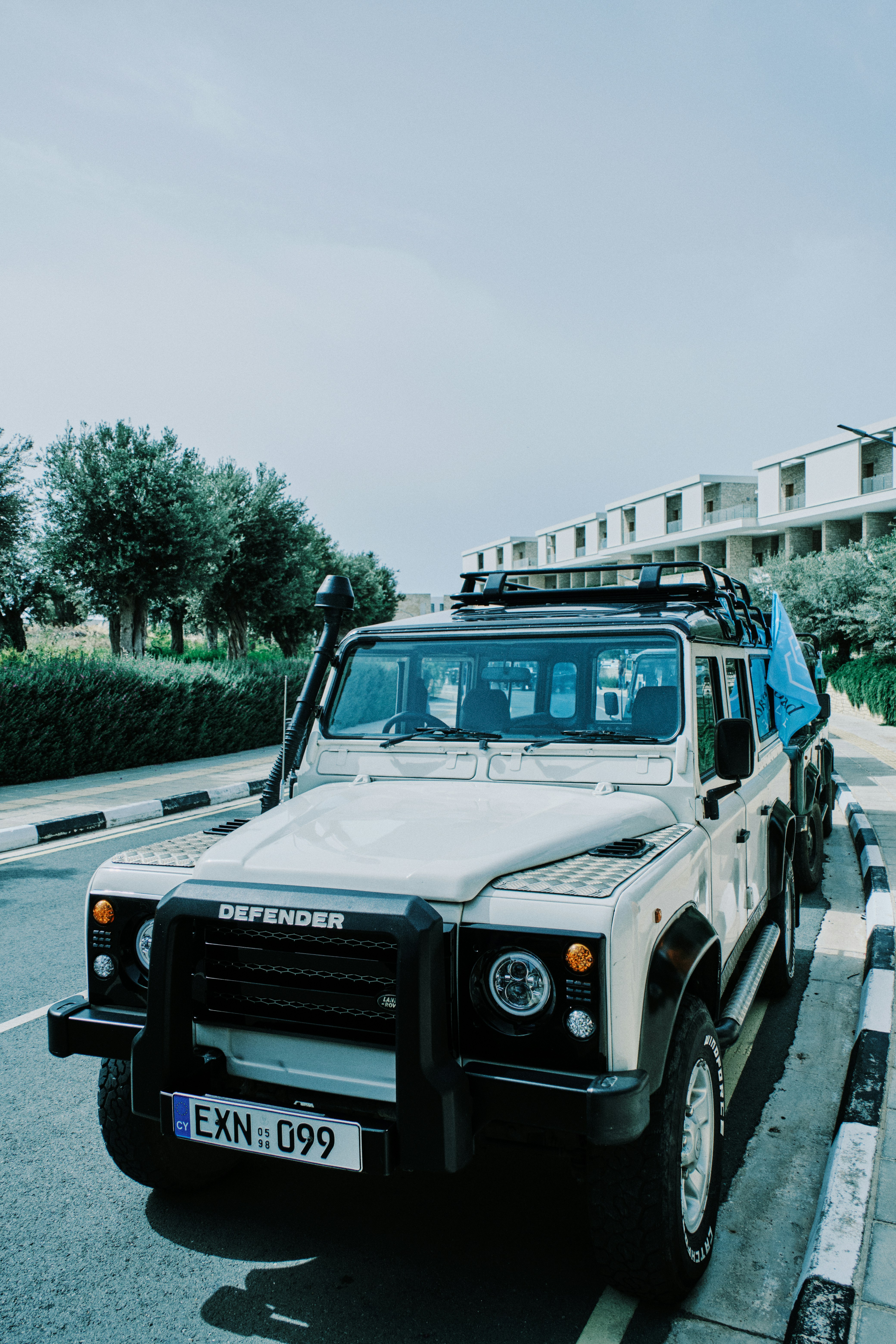 A white defender suv is parked on the road.