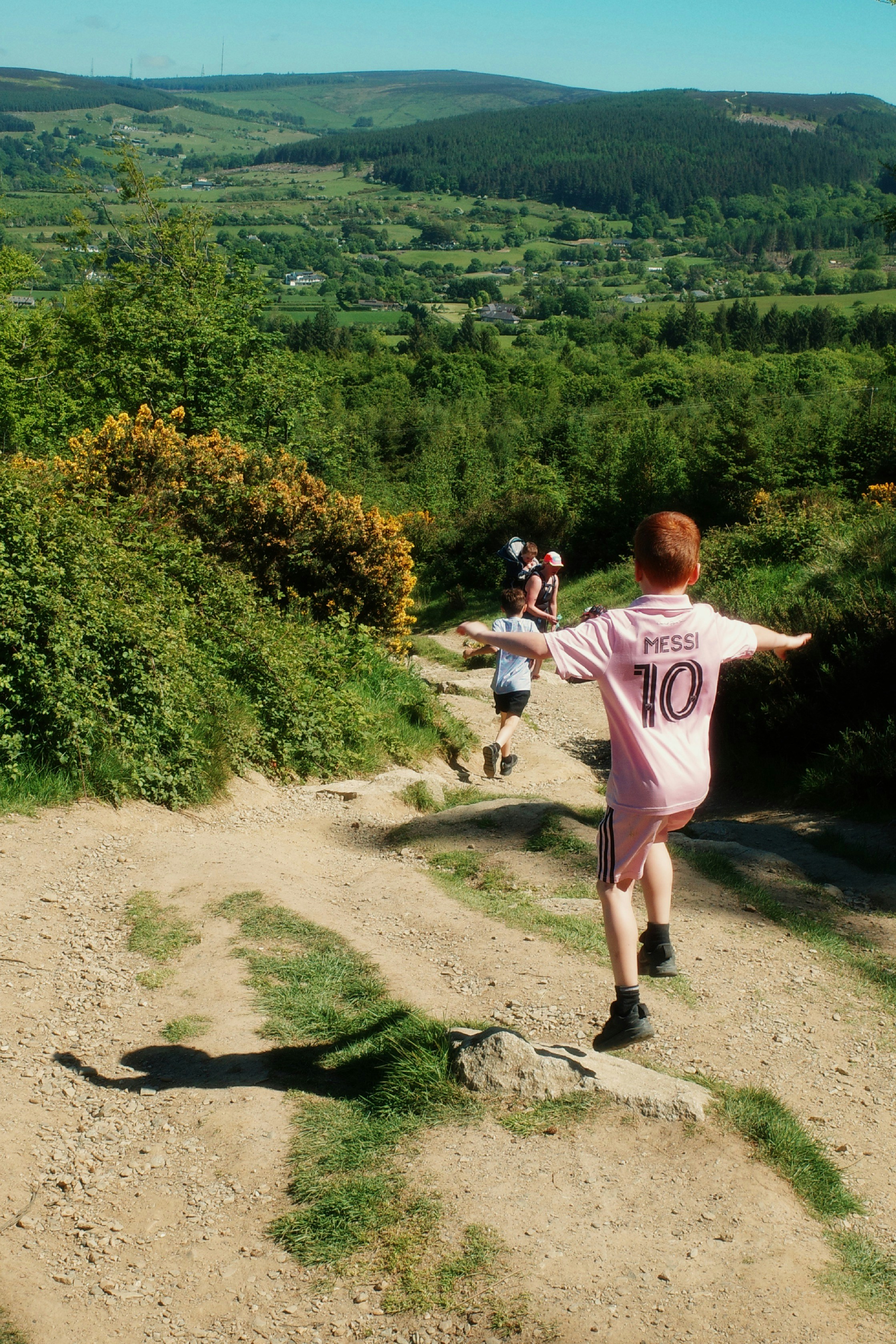 Children walking down a scenic outdoor trail with mountain views, photo from Unsplash