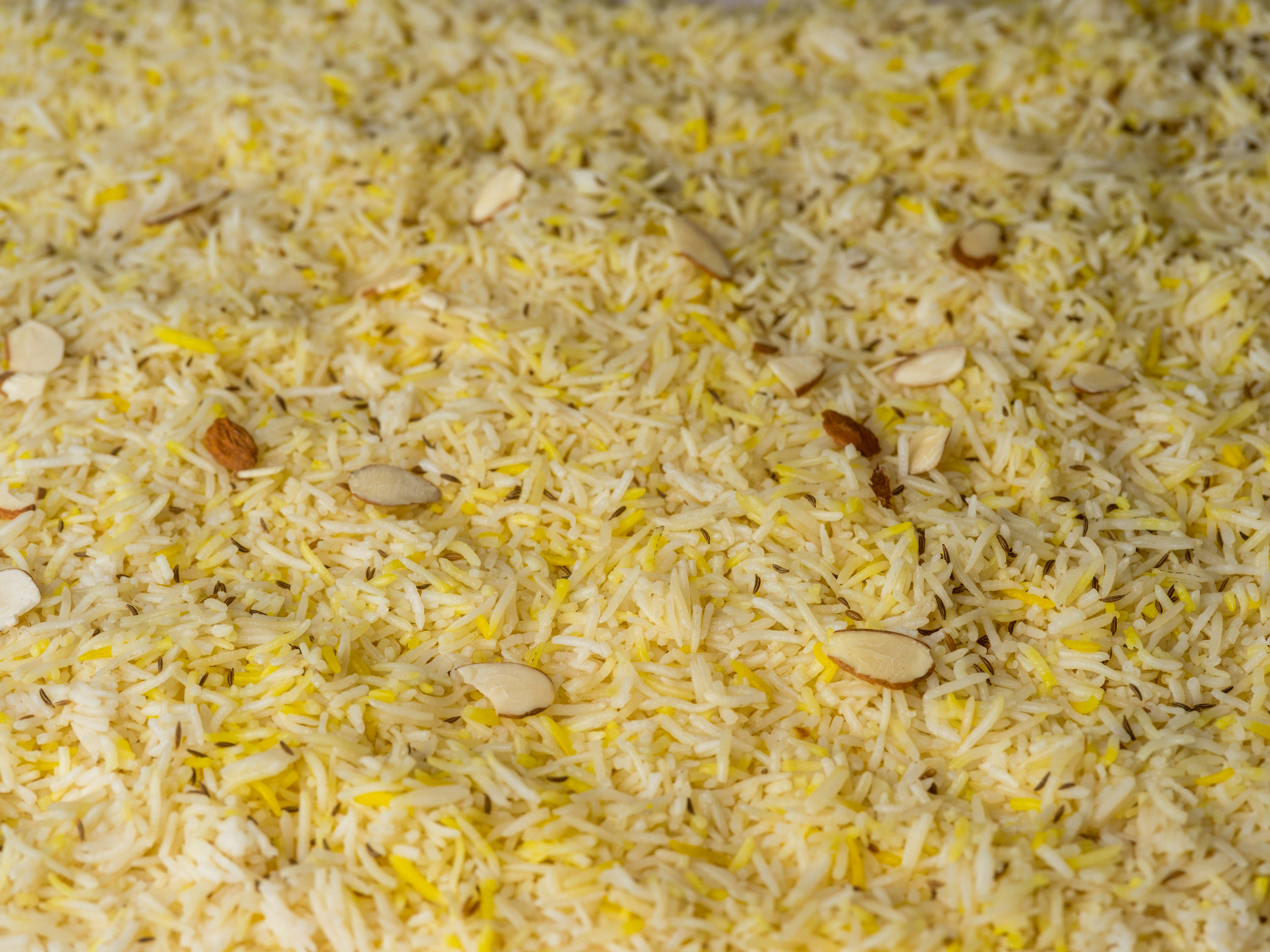 Yellow rice is topped with sliced almonds.
