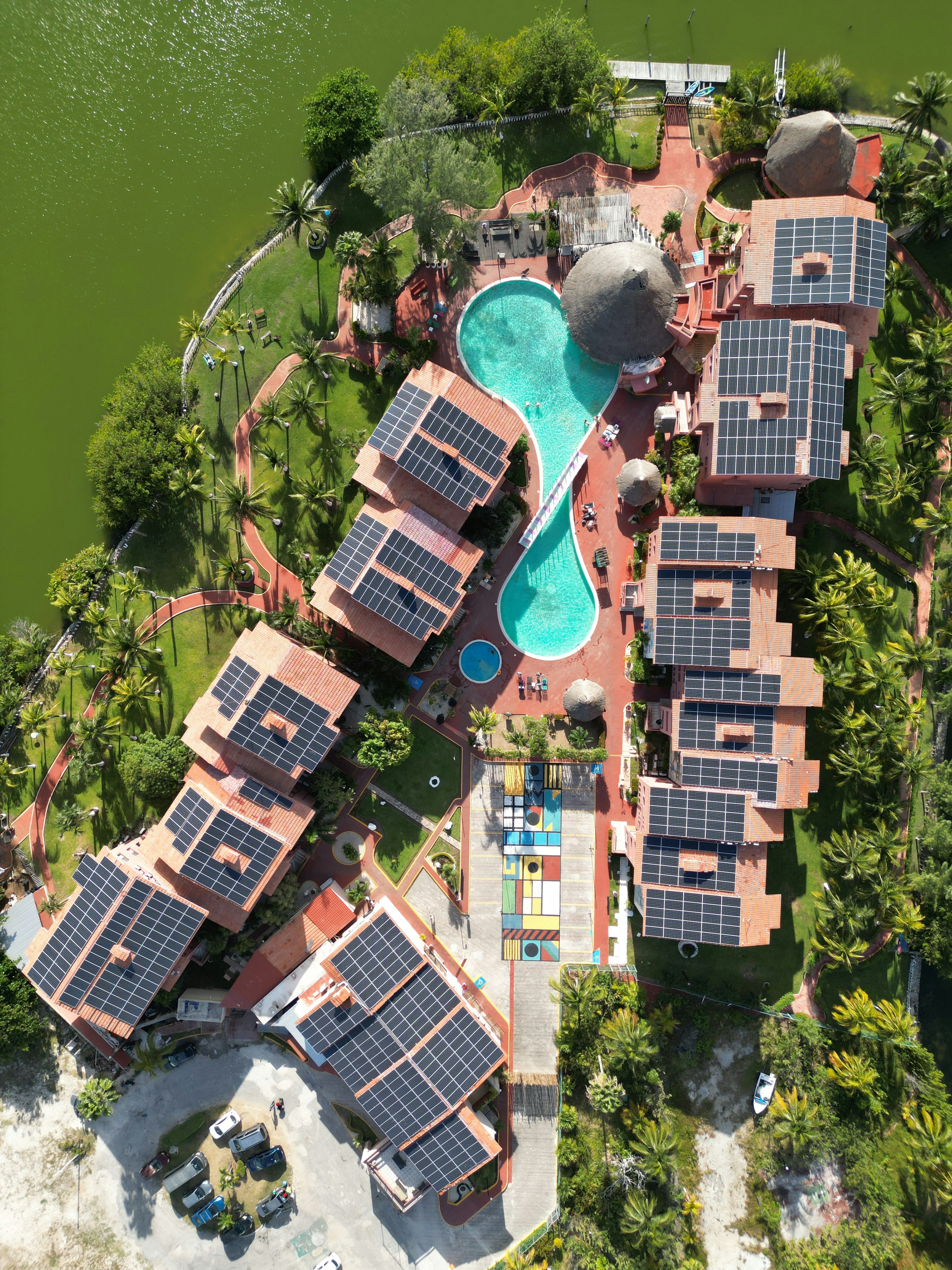 Resort with solar panels and a pool by the water.