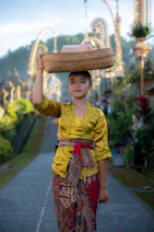 A woman balances a basket on her head.