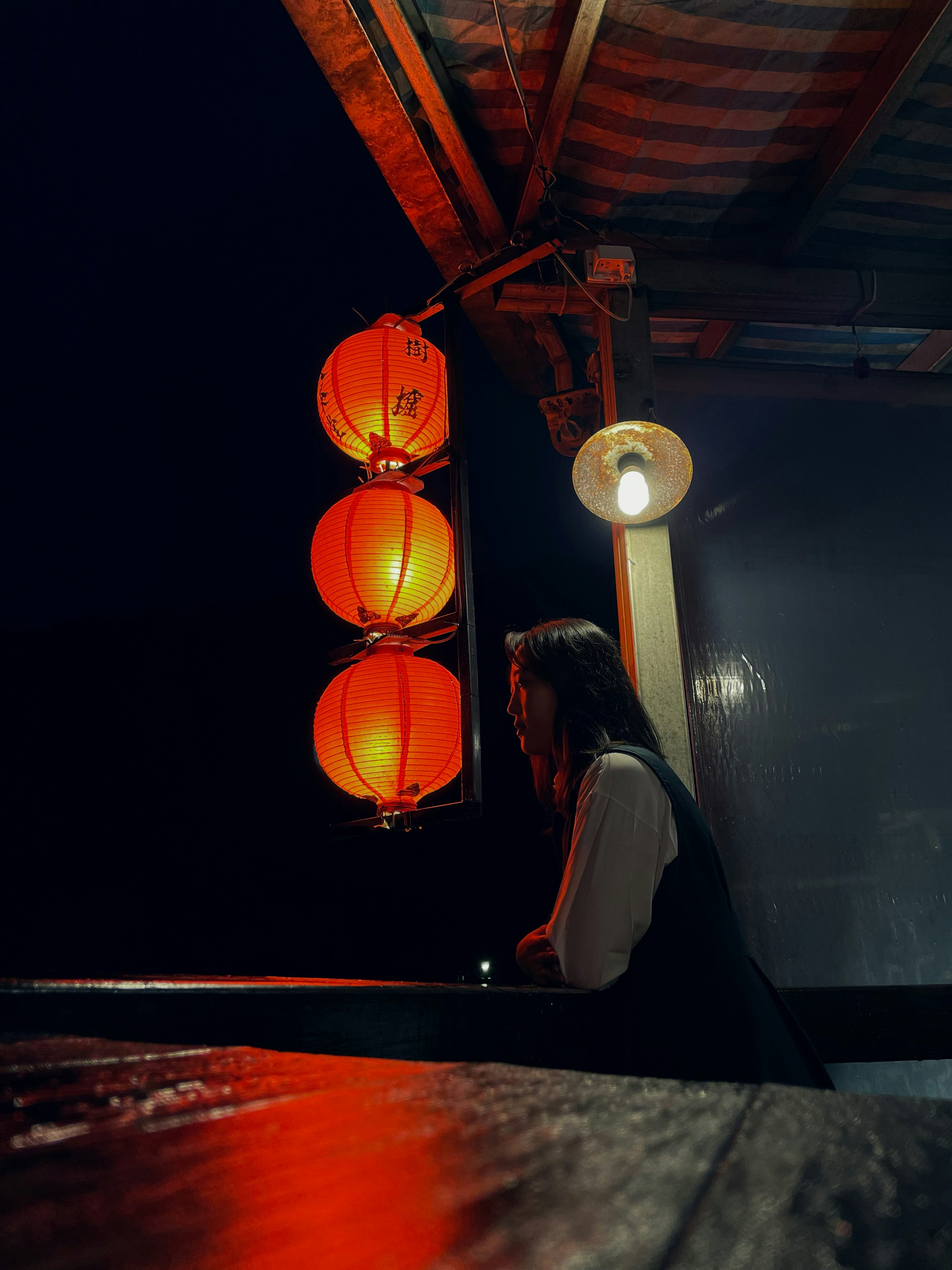 Woman watches lanterns glow in the night.