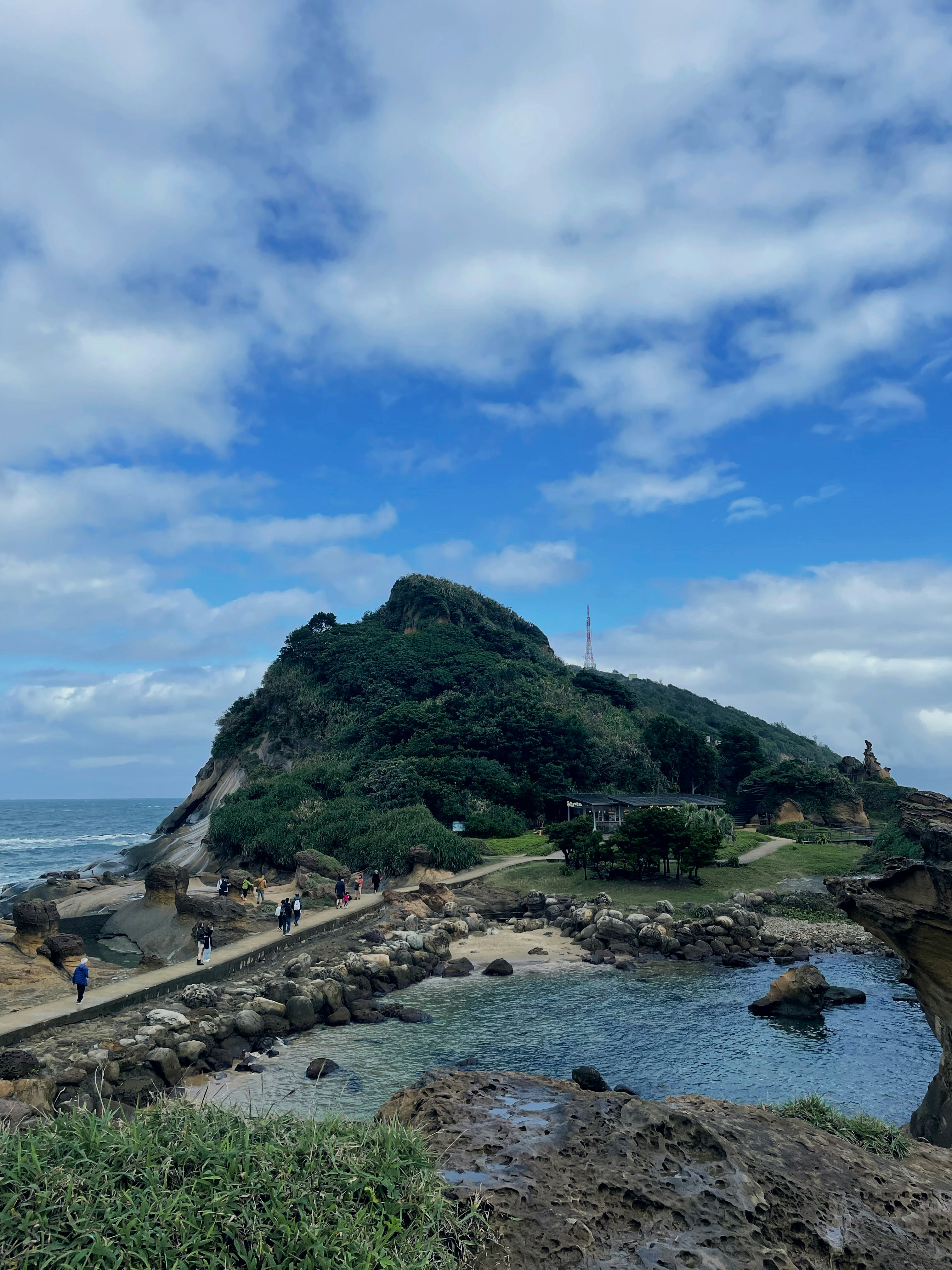 Rocky coast and hill under a bright blue sky.