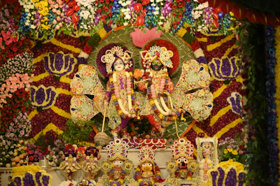 Krishna and radha idols, decorated with flowers.