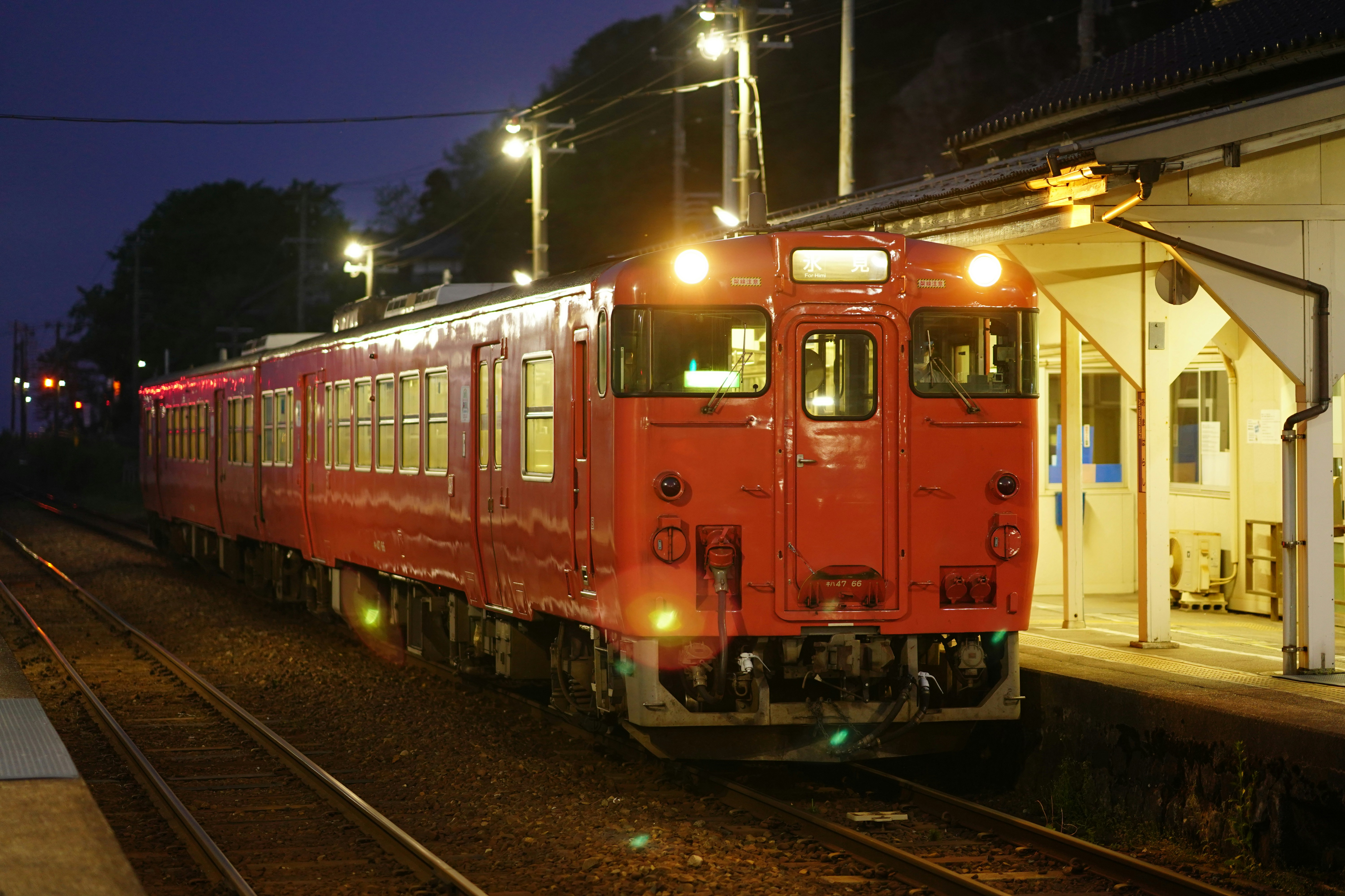 A red train pulls into a station at night.