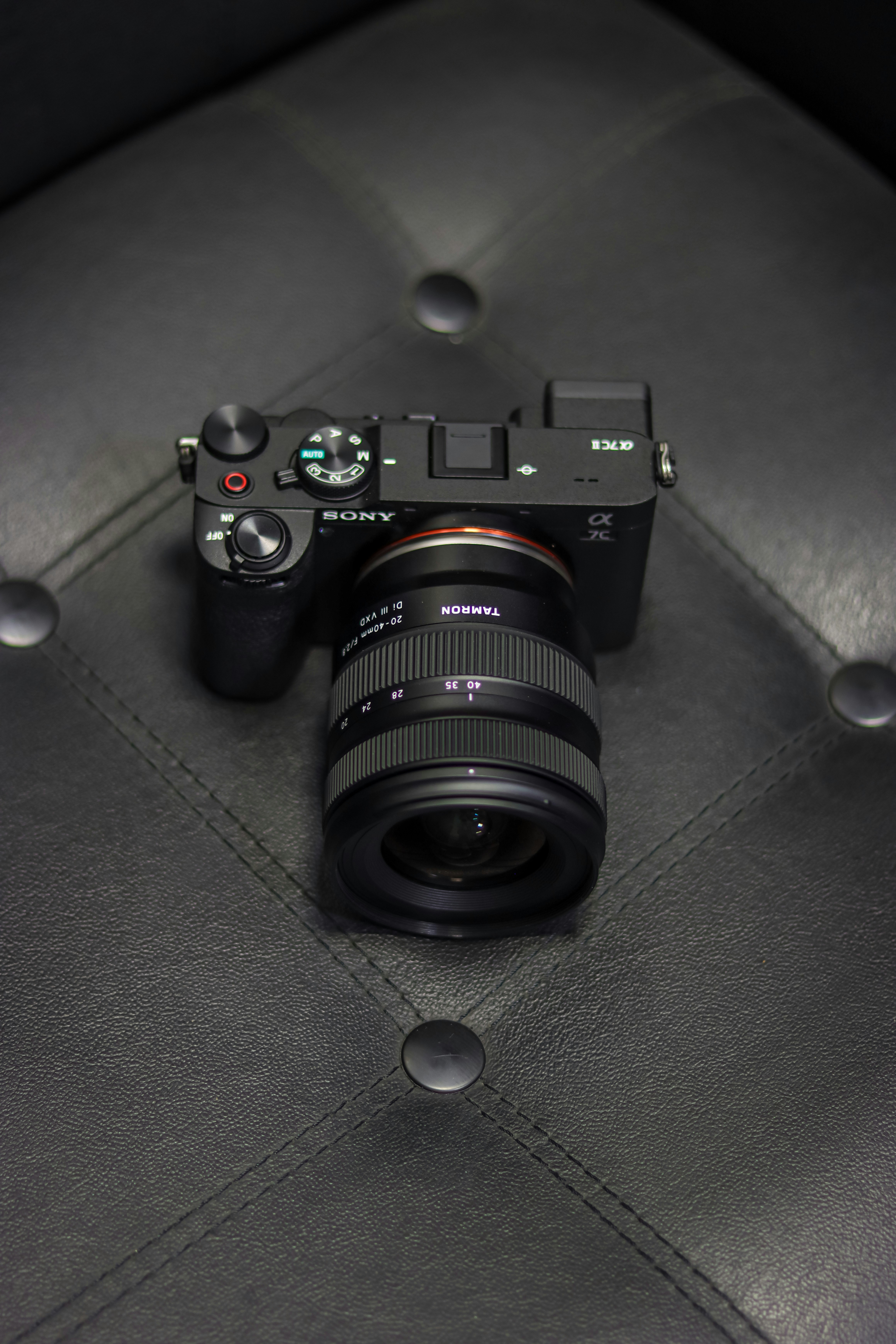 A sony camera sits on a leather surface.