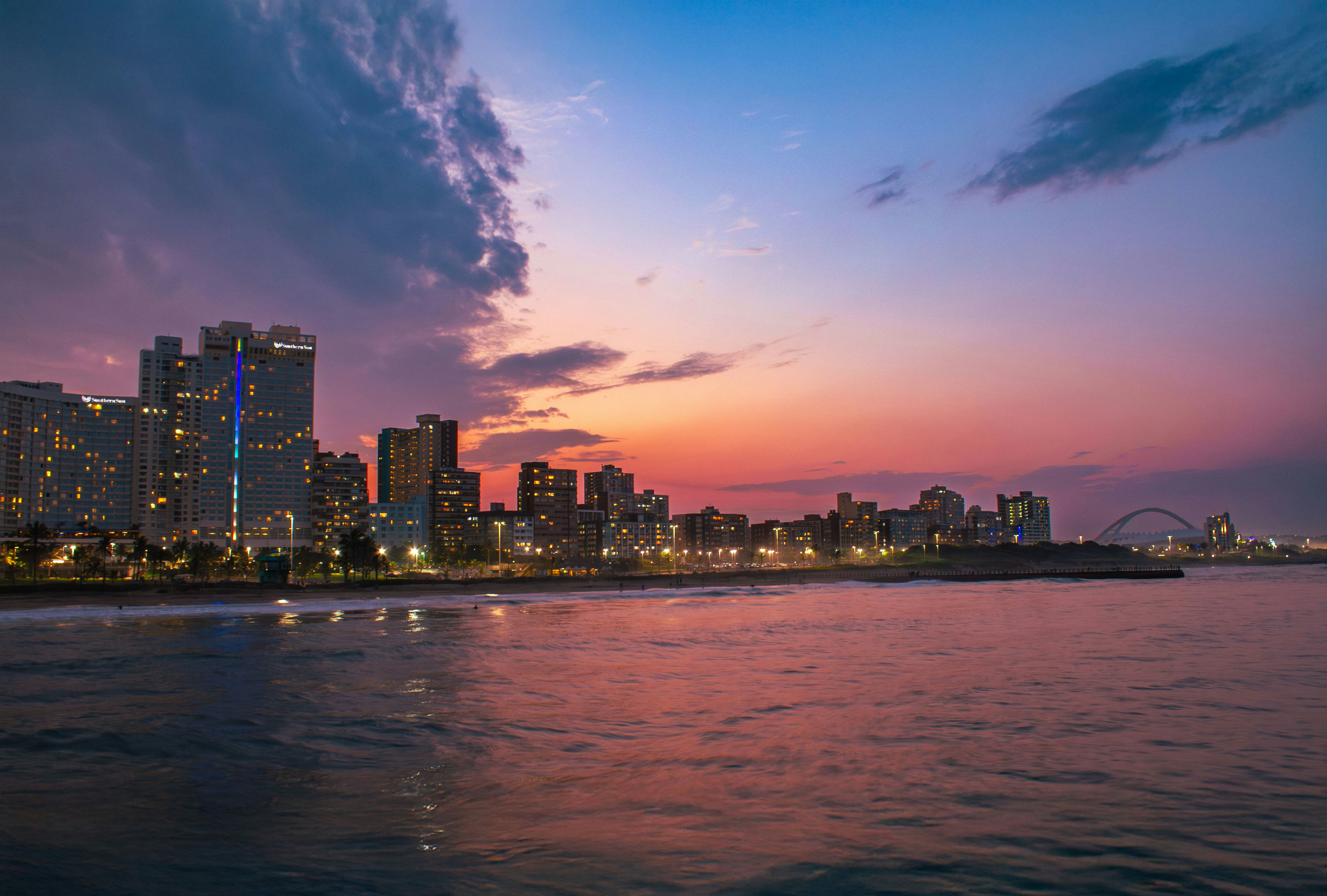 Cityscape silhouettes against a colorful, serene sunset.